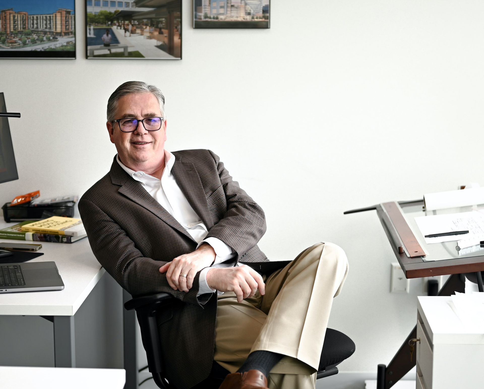 A man in a suit is sitting in a chair in front of a desk.