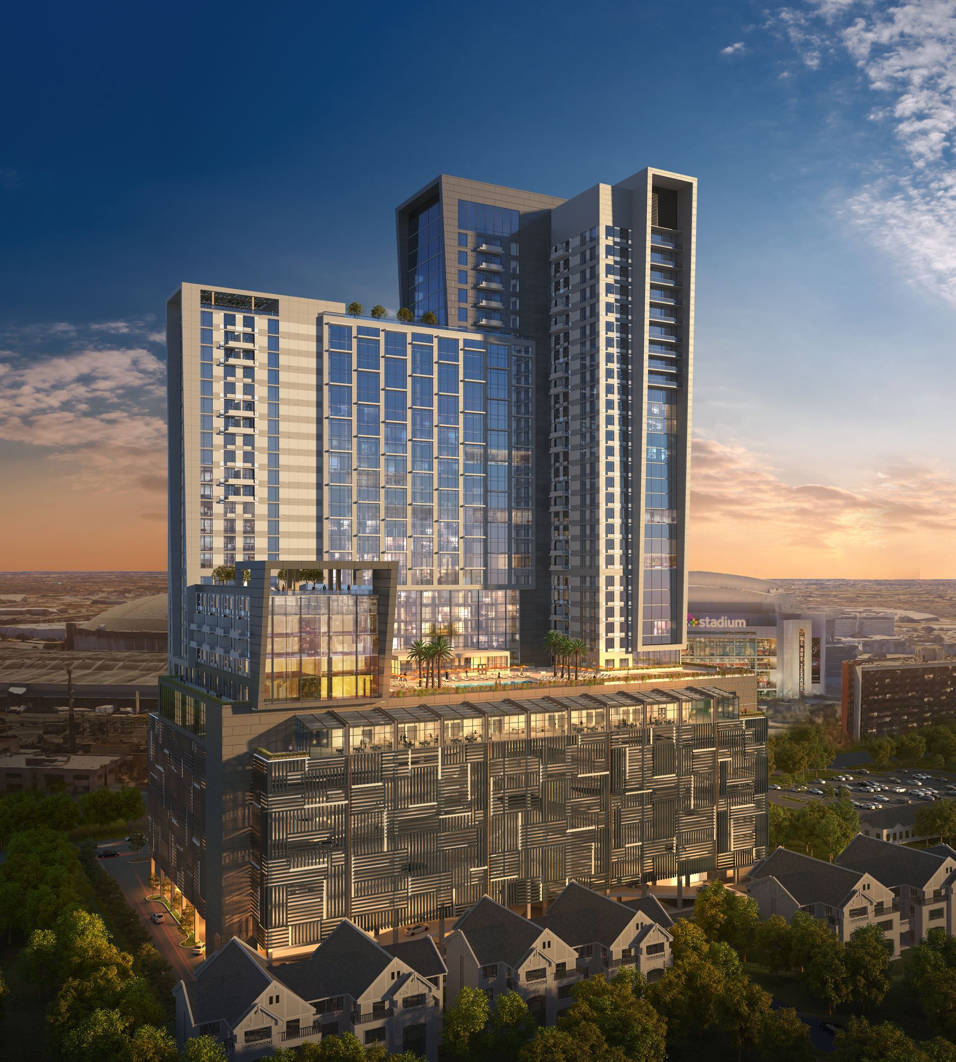 A large building with a lot of windows is surrounded by houses and trees.