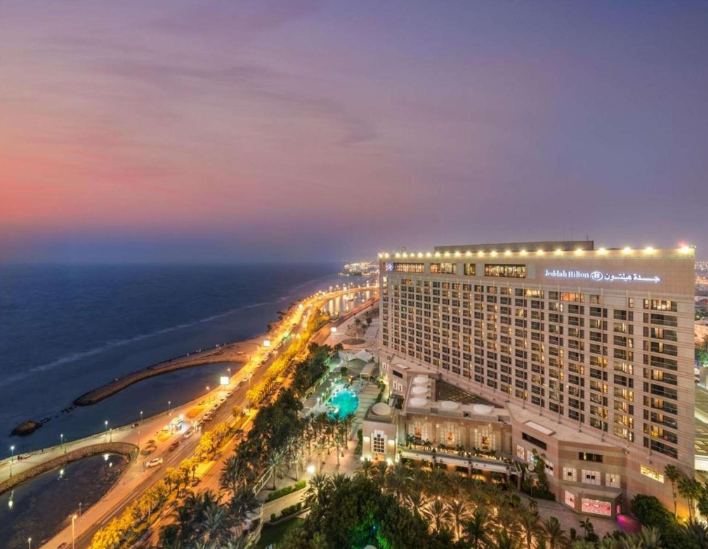 An aerial view of a large hotel next to the ocean at night.