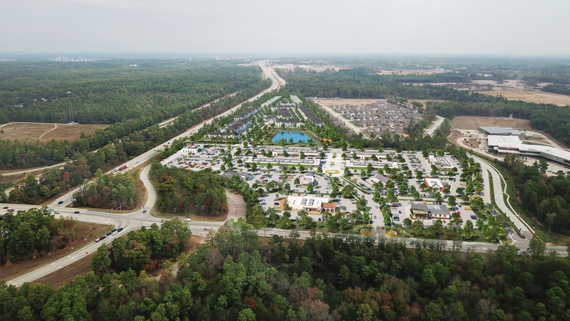 An aerial view of a residential area surrounded by trees and a highway.