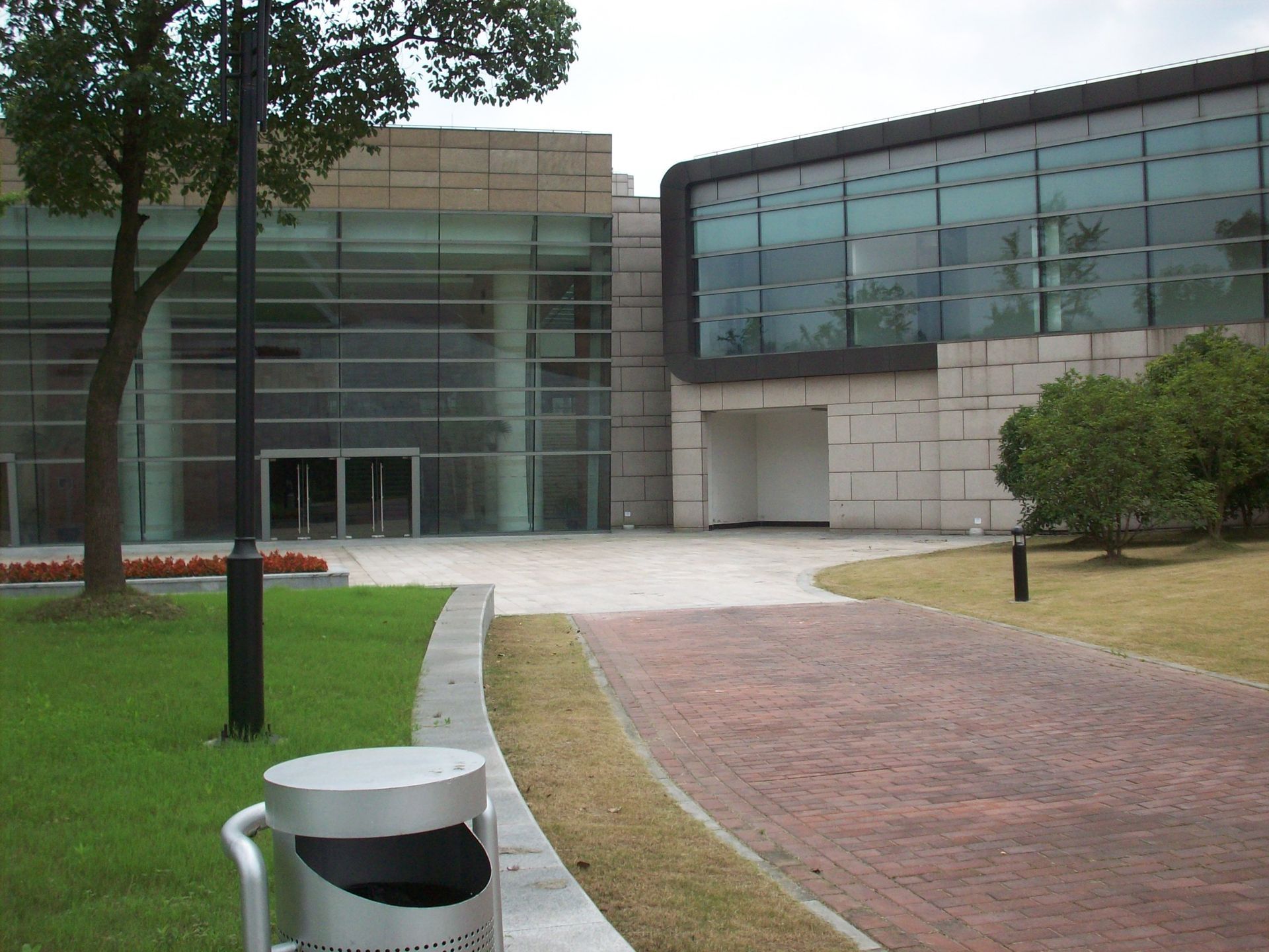 A trash can sits in front of a large building