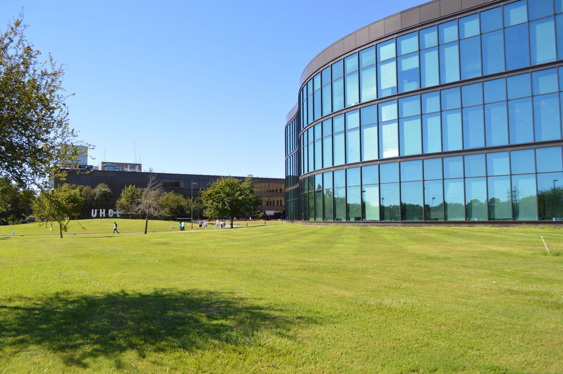 A large building with a lot of windows is surrounded by grass and trees