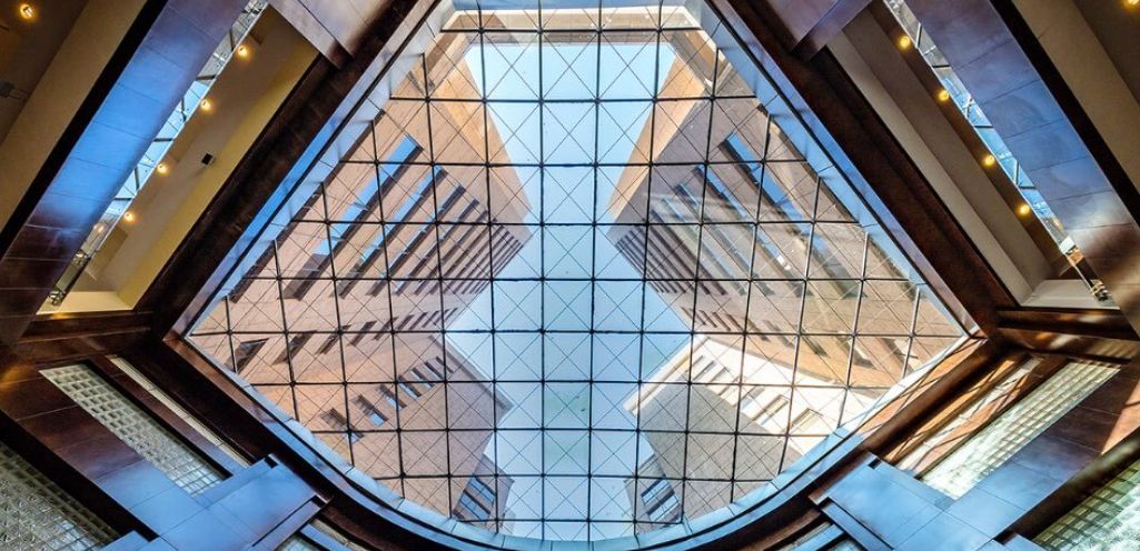 Looking up at the ceiling of a building with a stained glass window.