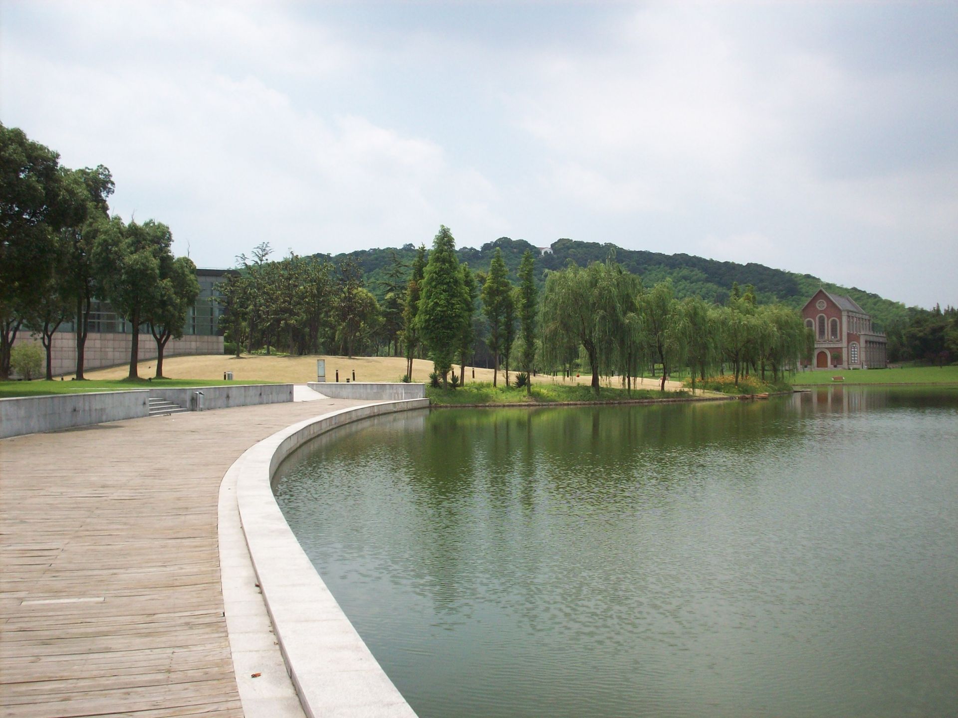 A lake in a park with trees and a building in the background