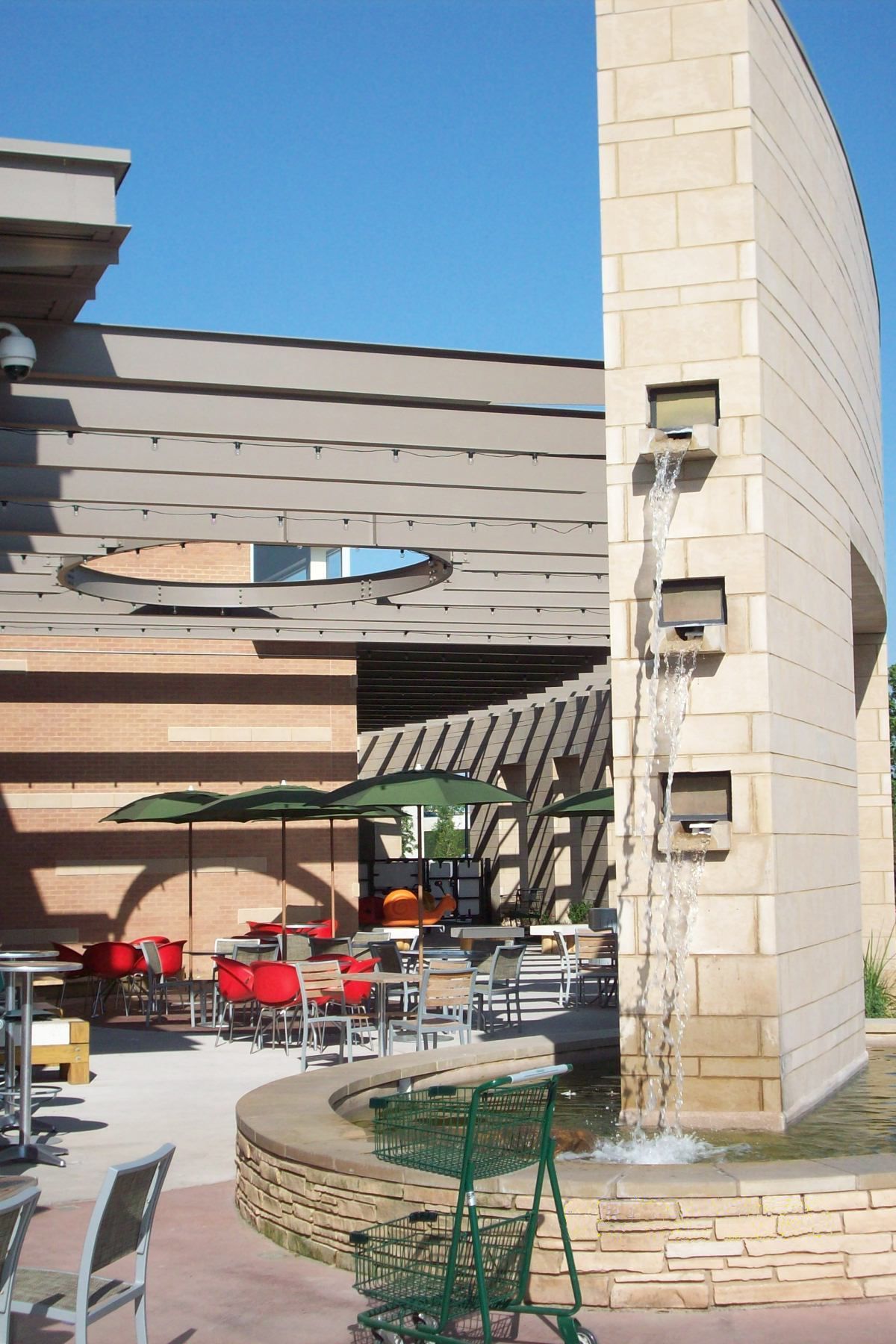 A fountain in front of a building with tables and chairs