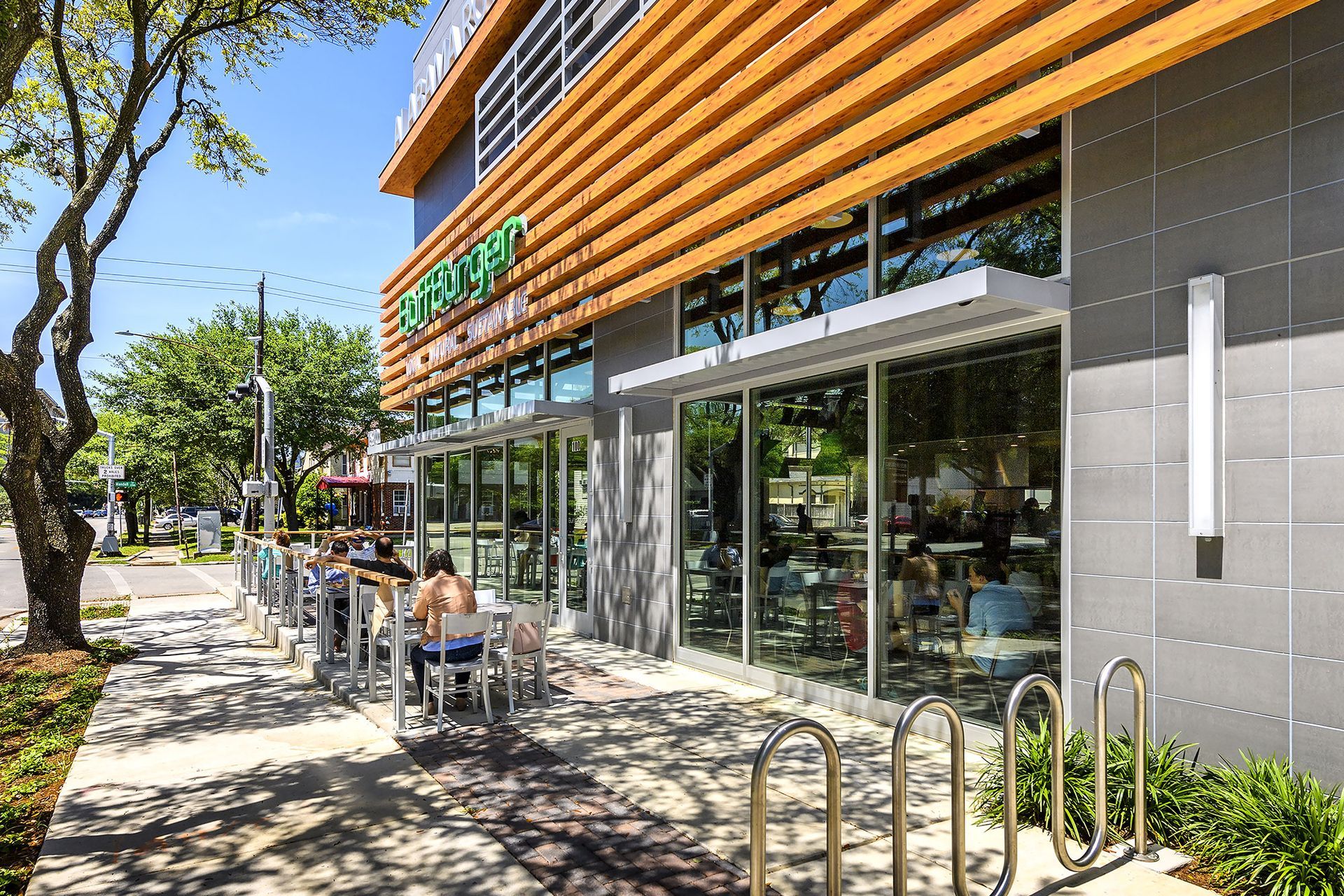 A group of people are sitting at tables outside of a restaurant.