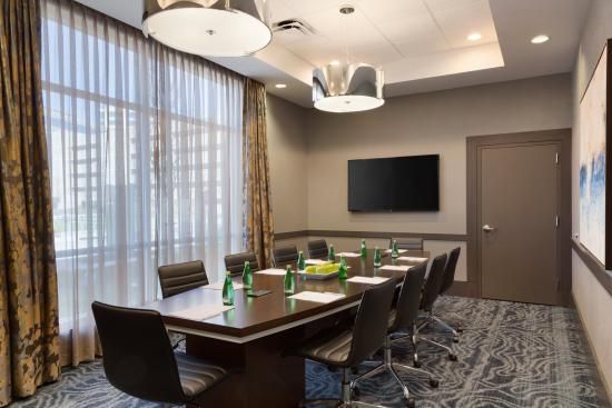 A conference room with a long table and chairs and a flat screen tv.
