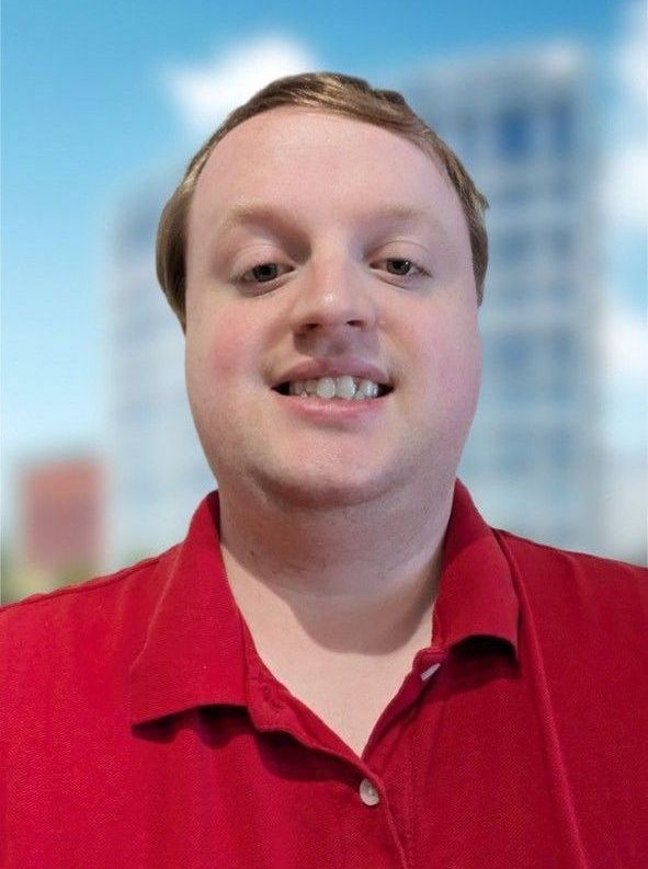 A man in a red shirt is smiling for the camera.