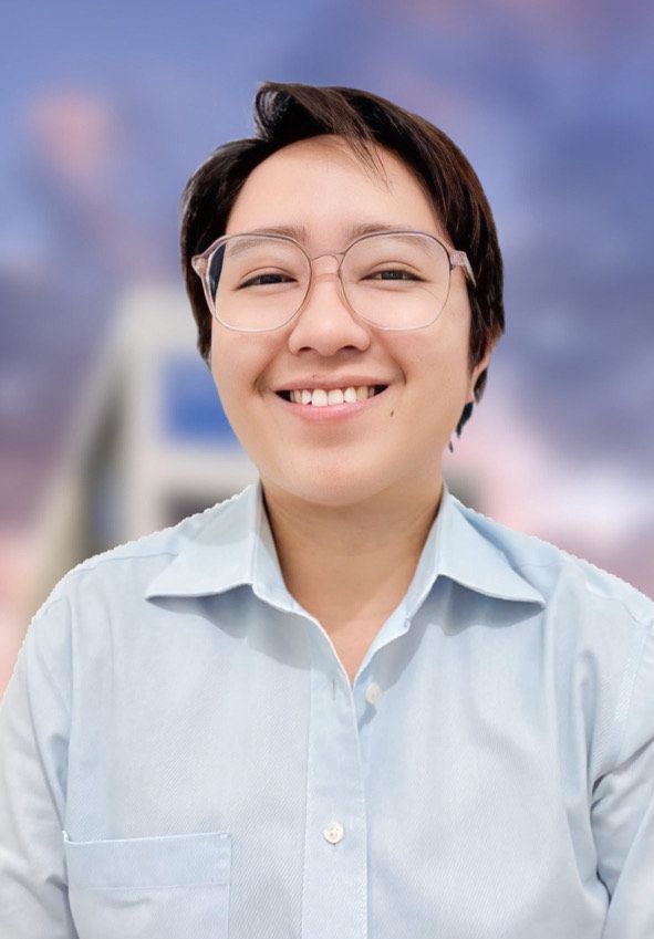 A woman wearing glasses and a blue shirt is smiling for the camera.
