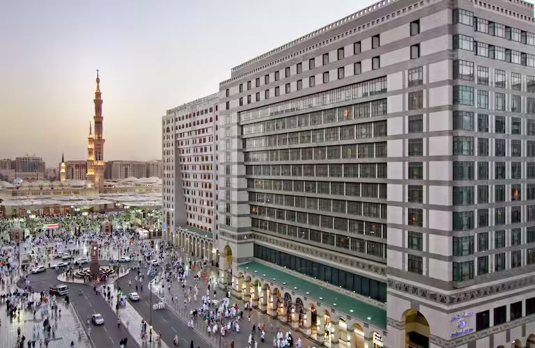 An aerial view of a large building with a mosque in the background.