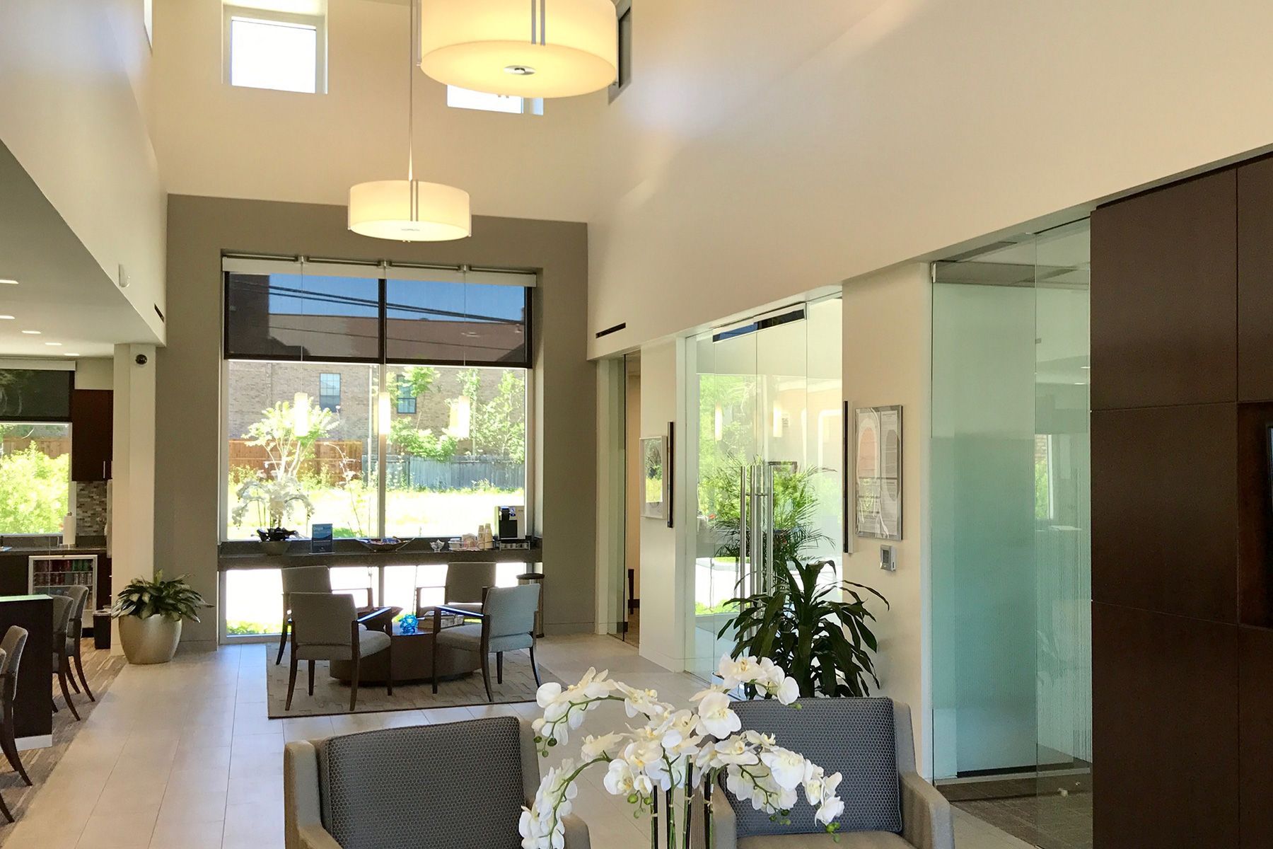 A living room with a lot of windows and a couch and chairs