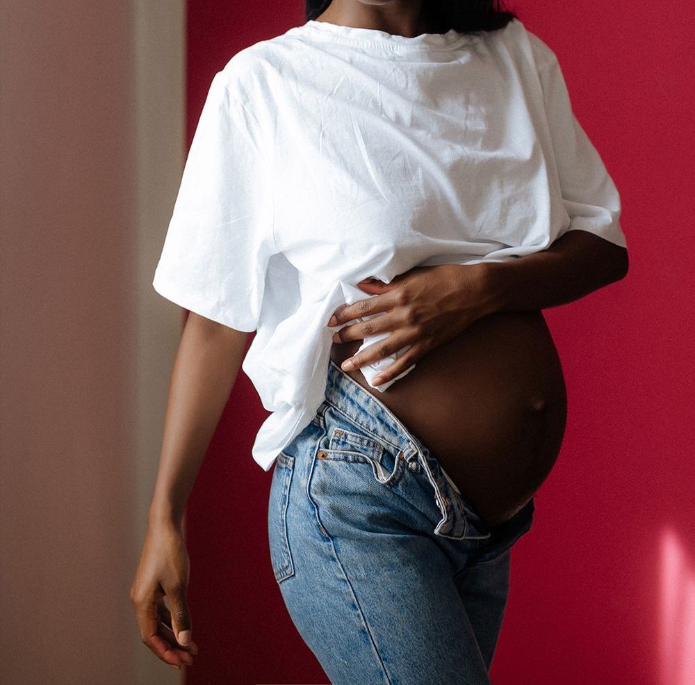 zwangere buik, omringd door een warme gloed van natuurlijk licht