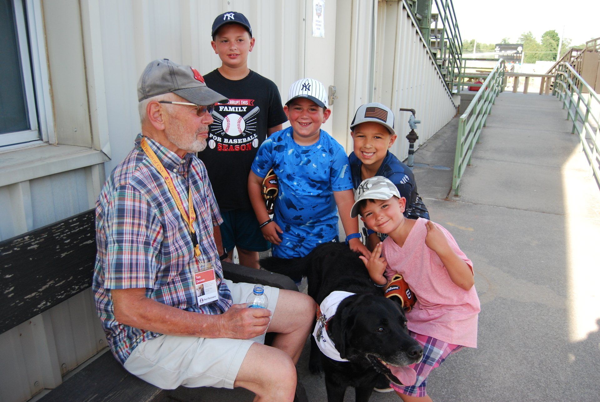 A man is sitting on a bench with three children and a dog.