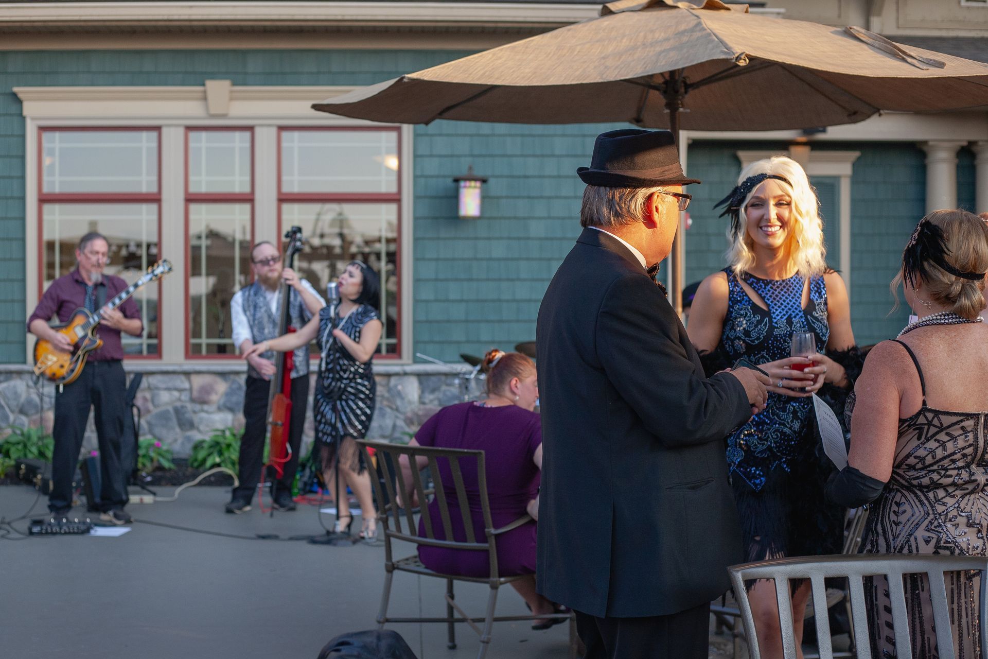 A group of people are standing under an umbrella in front of a building.