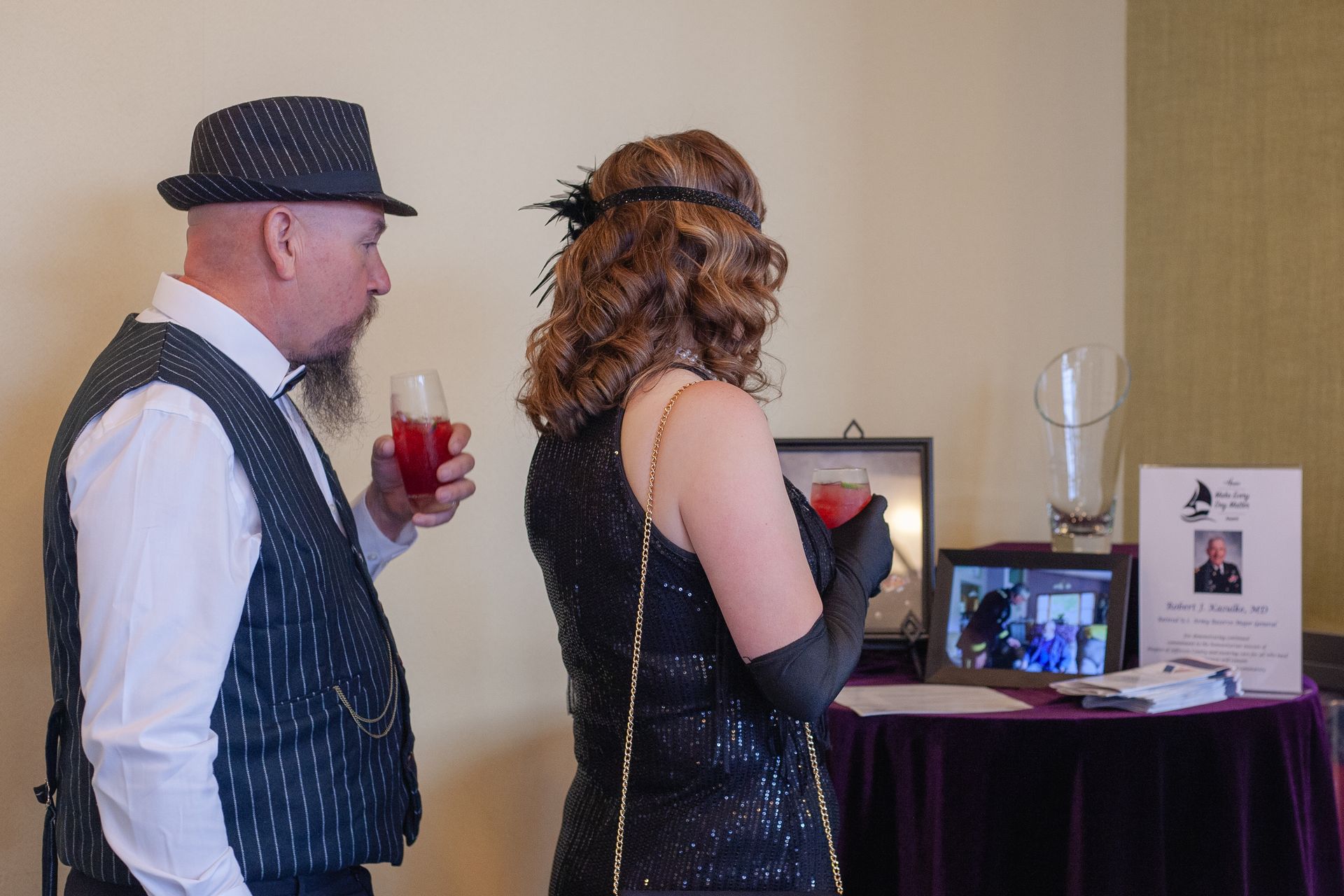 A man and a woman are standing next to each other holding drinks.