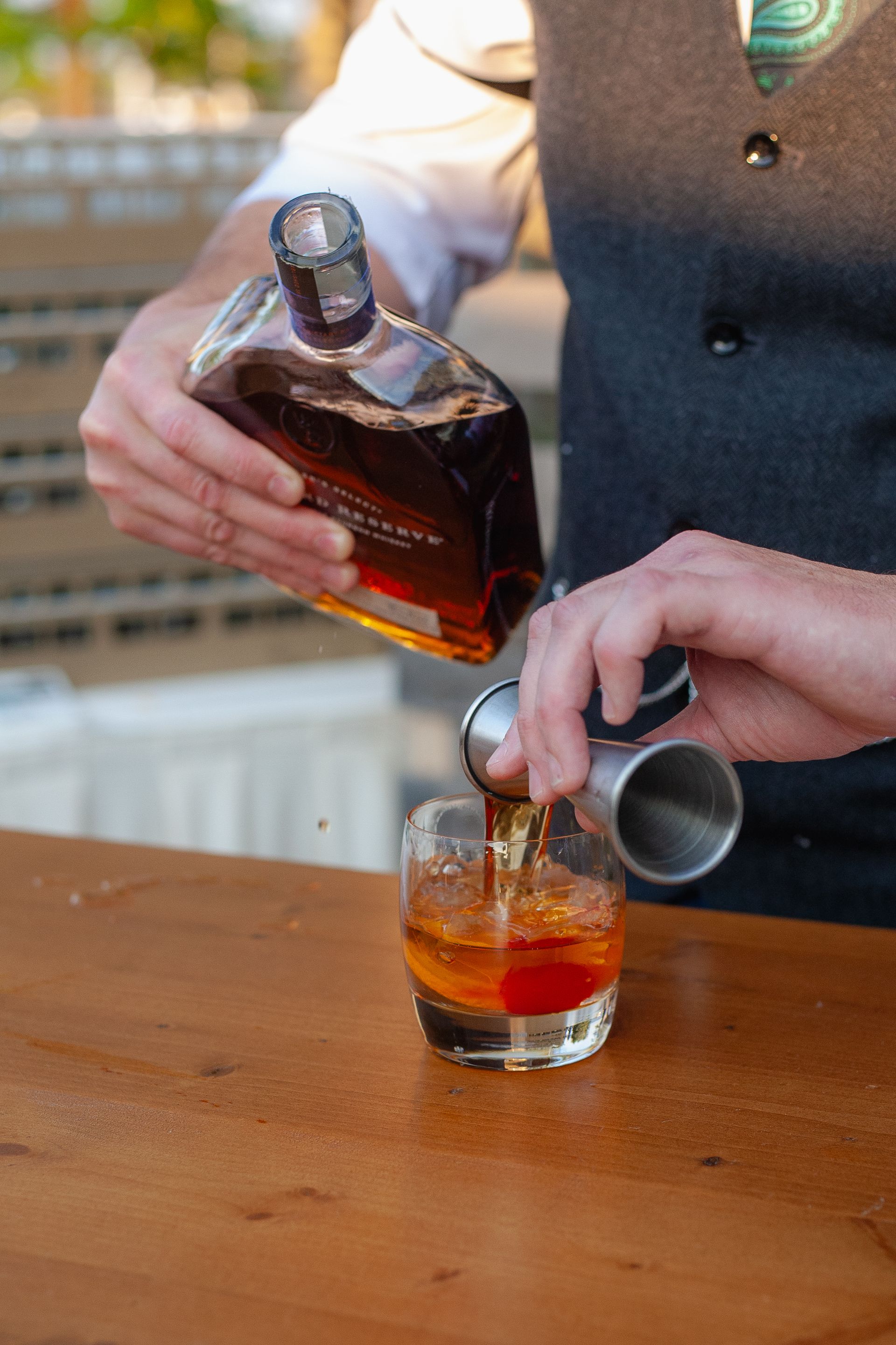 A man is pouring a drink from a bottle into a glass.