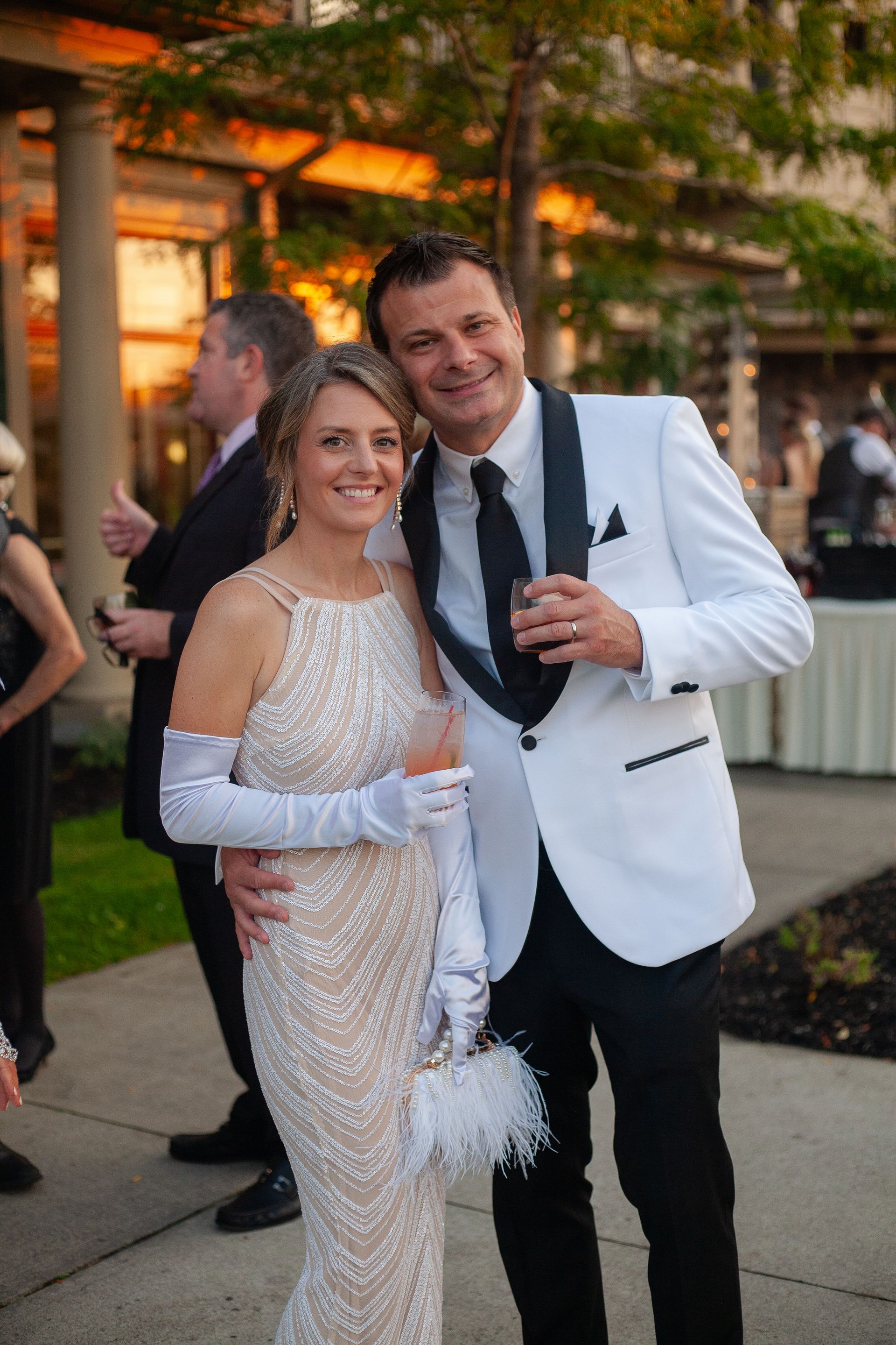 A man and a woman are posing for a picture on a sidewalk.