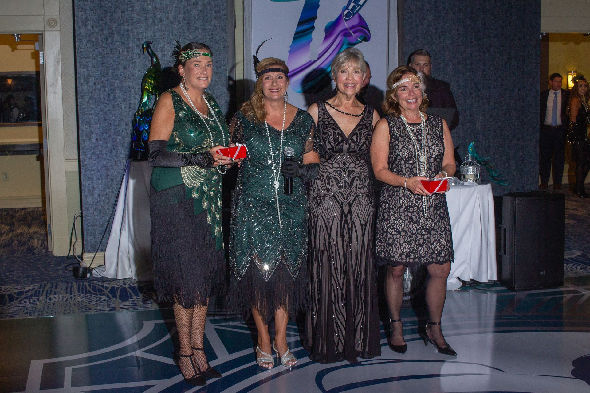 A group of women in flapper dresses are standing next to each other on a dance floor.