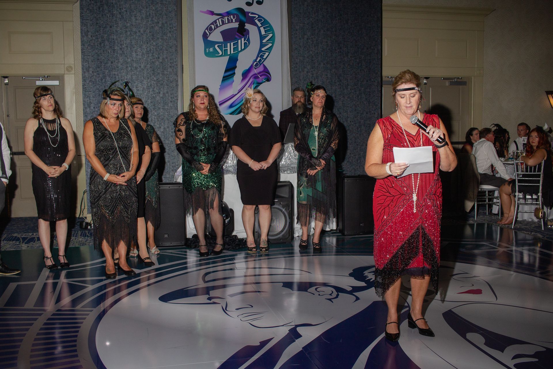 A woman in a red dress is giving a speech at a party.