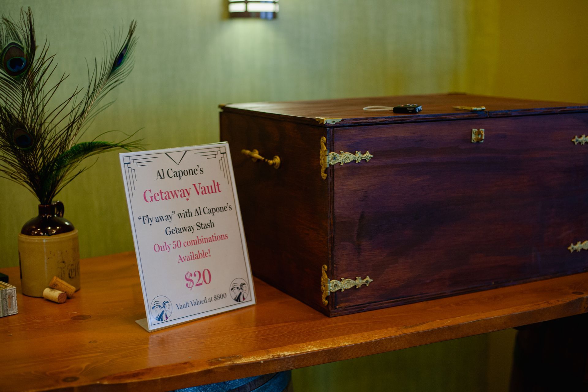 A wooden box is sitting on a wooden table next to a peacock feather.