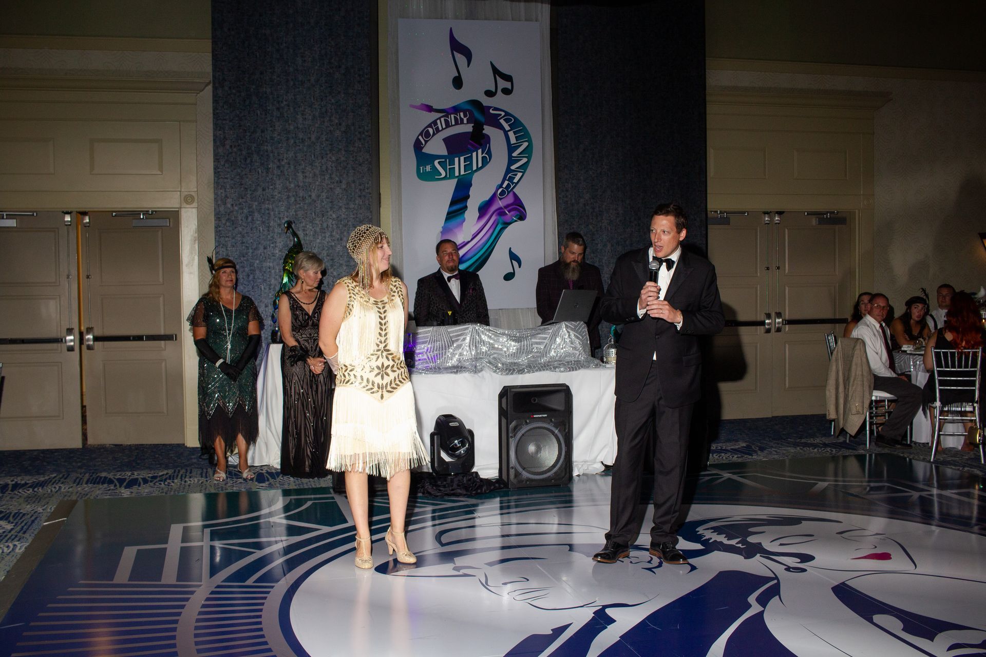 A man in a tuxedo stands next to a woman on a dance floor
