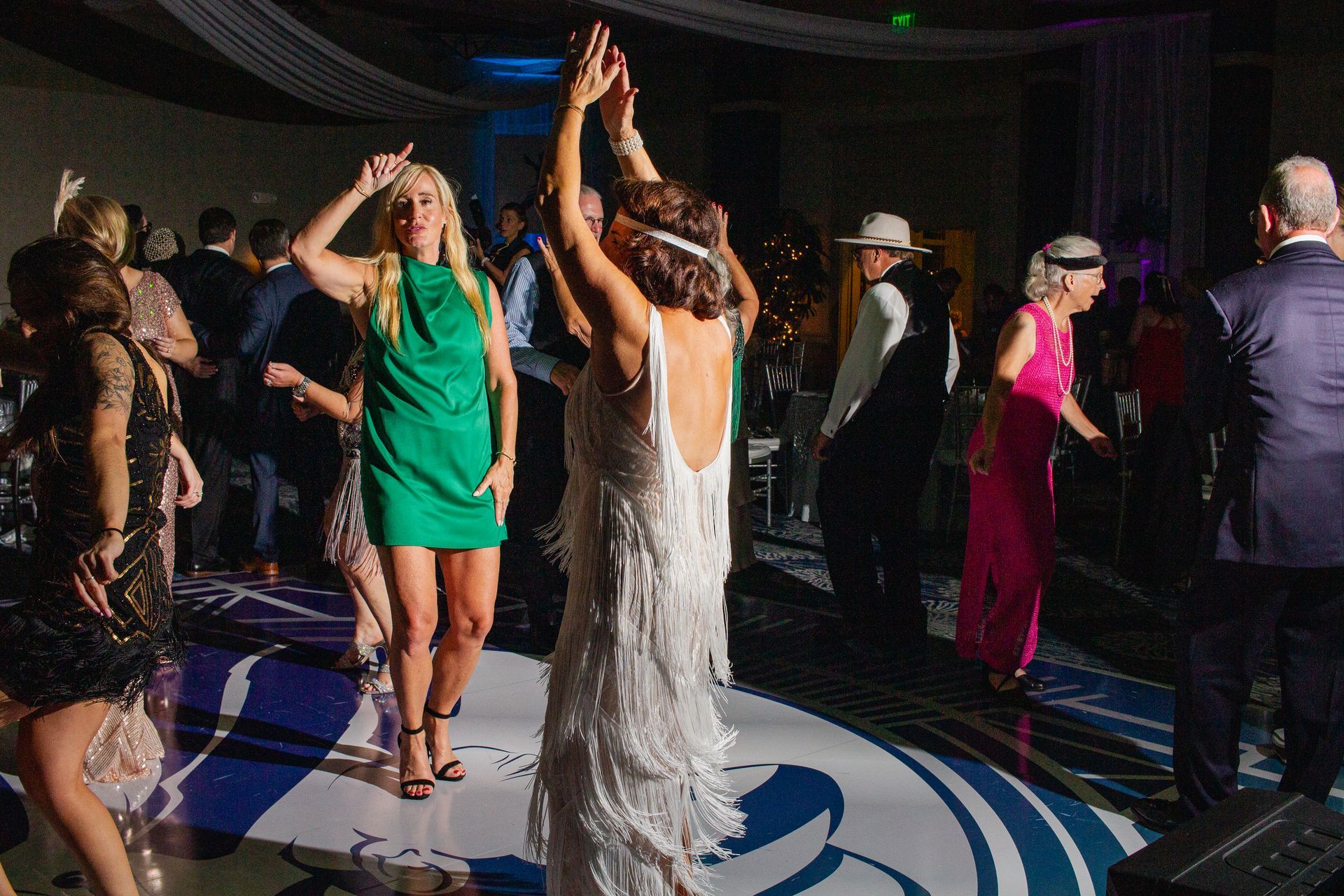 A group of people are dancing on a dance floor at a wedding reception.