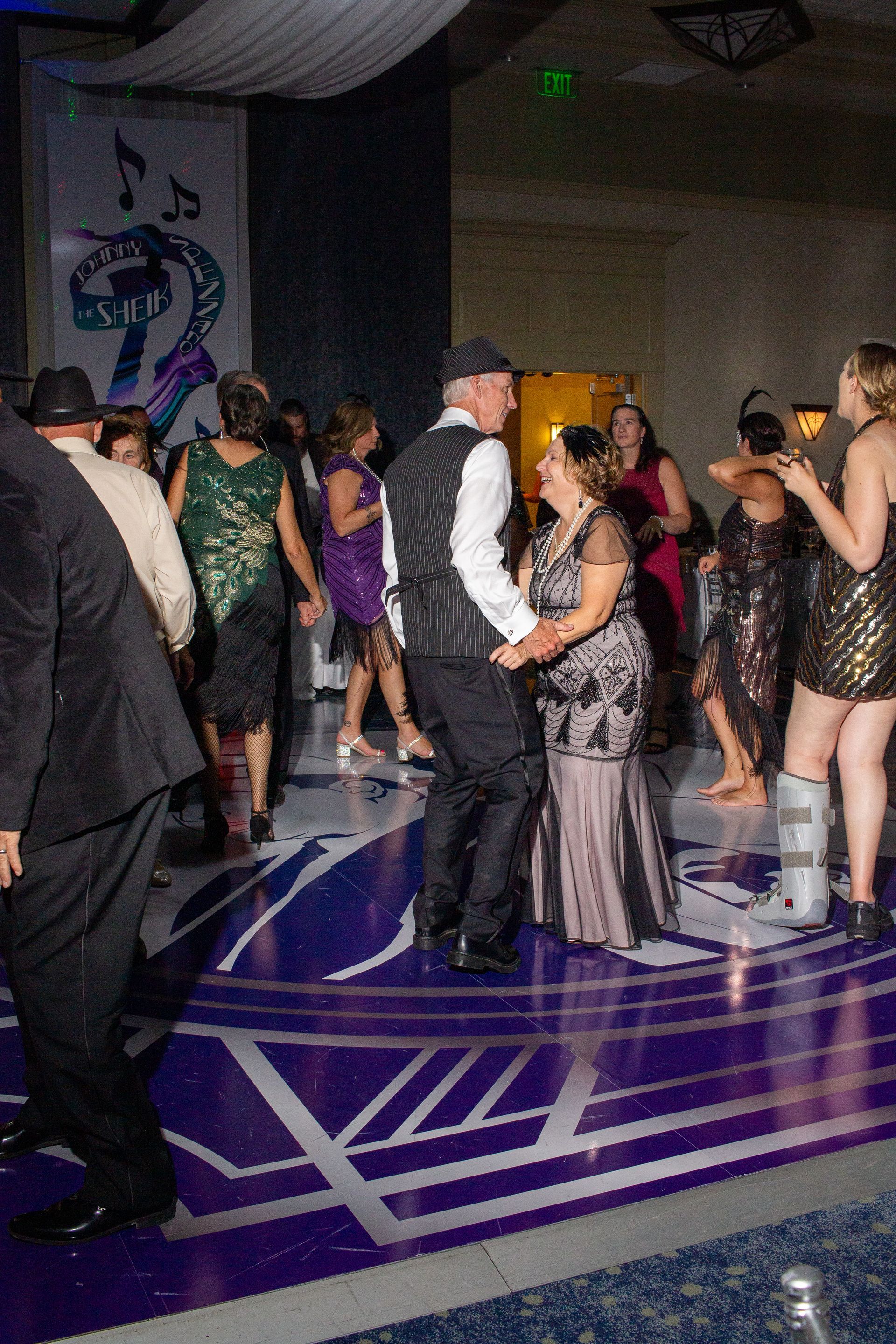 A group of people are dancing on a purple dance floor.
