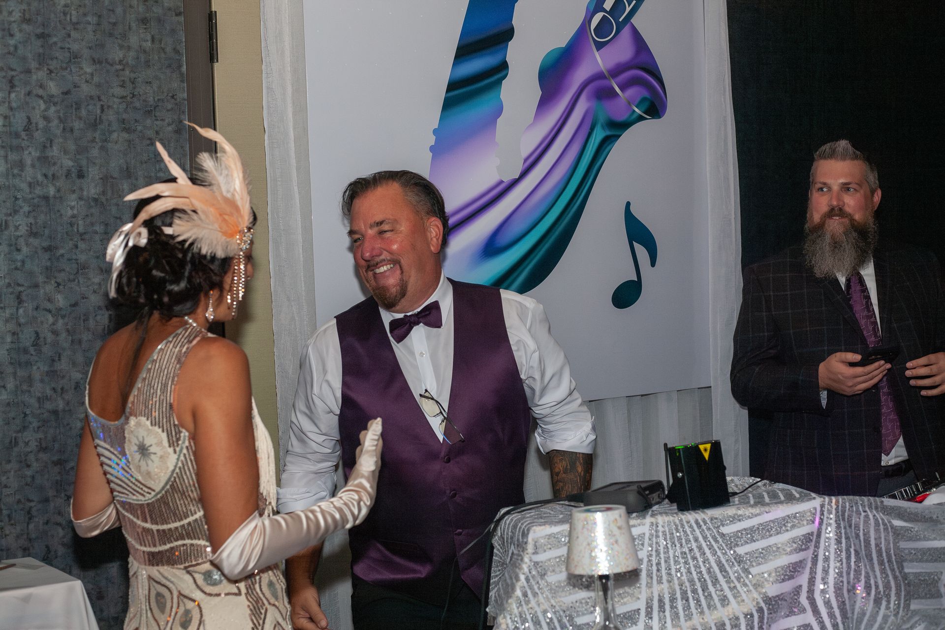 A man in a purple vest is dancing with a woman in a white dress.