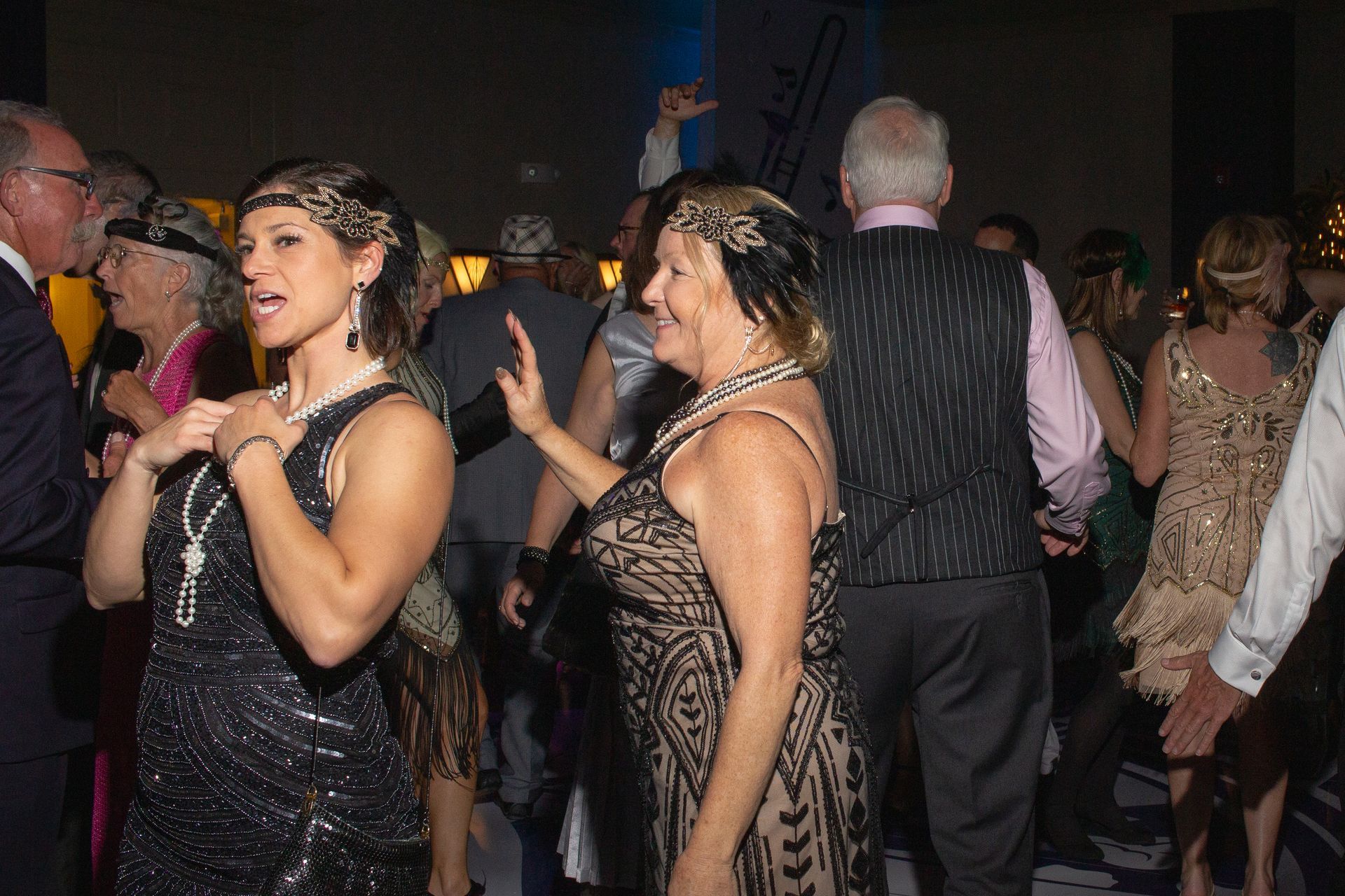 Two women are dancing in a crowd of people at a party.