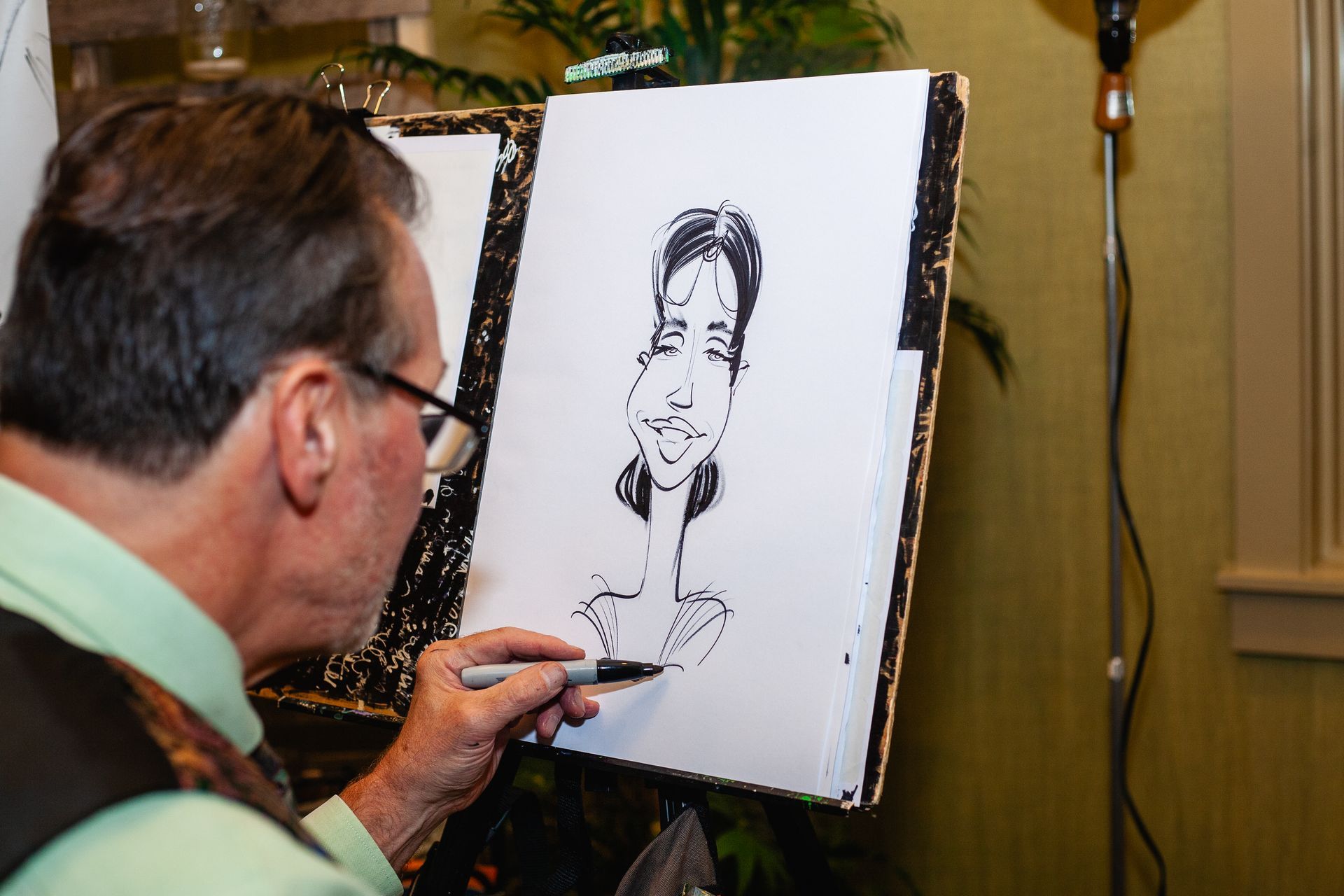 A man is drawing a caricature of a woman on an easel