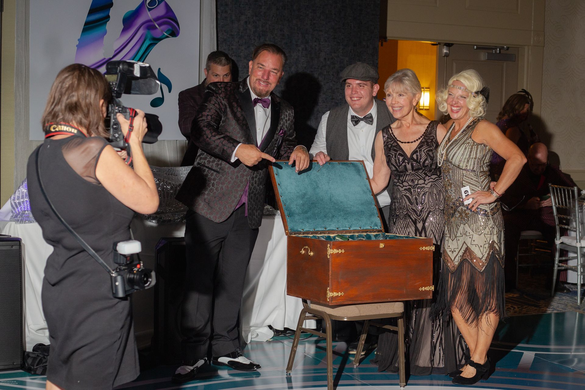 A woman is taking a picture of a group of people standing around a trunk.