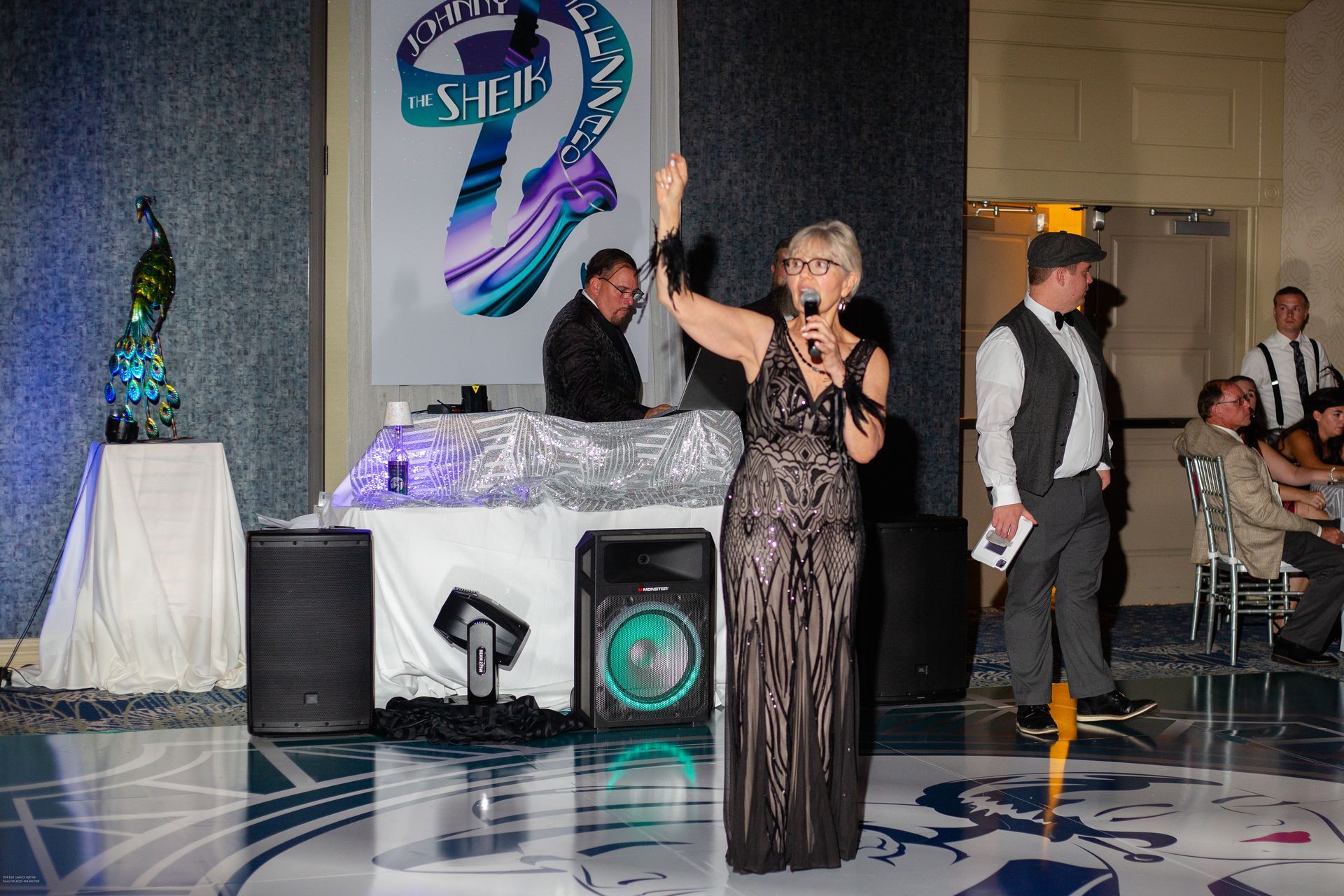 A woman in a black dress is standing on a dance floor holding a microphone.