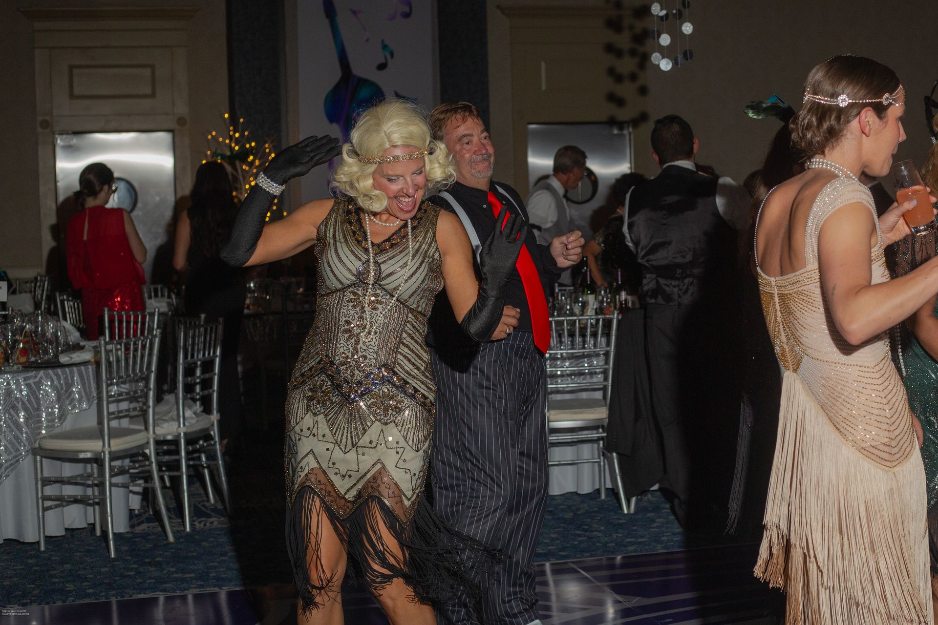 A woman in a flapper dress is dancing at a party.
