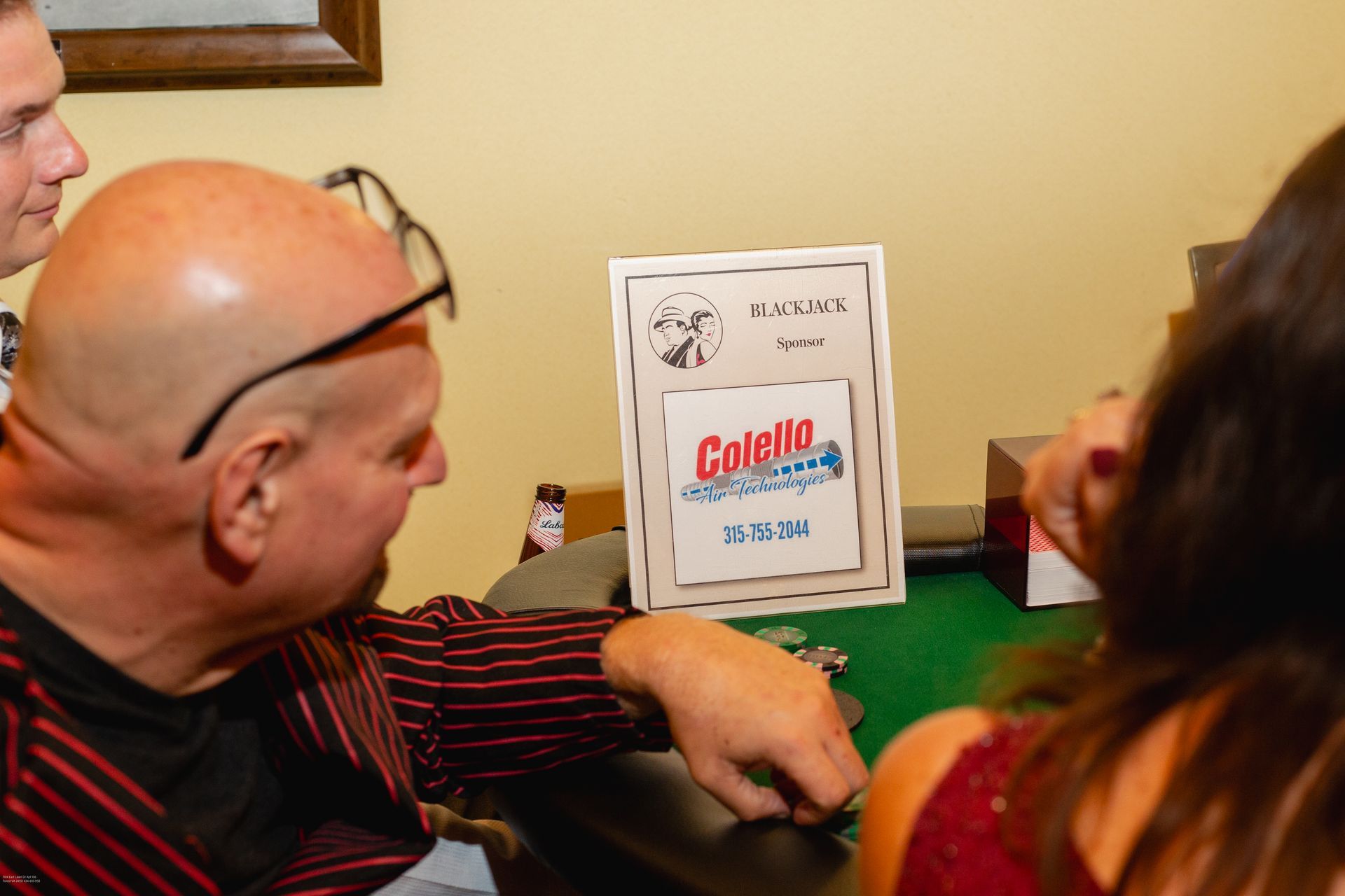 A man is sitting at a table with a sign that says colgate on it.