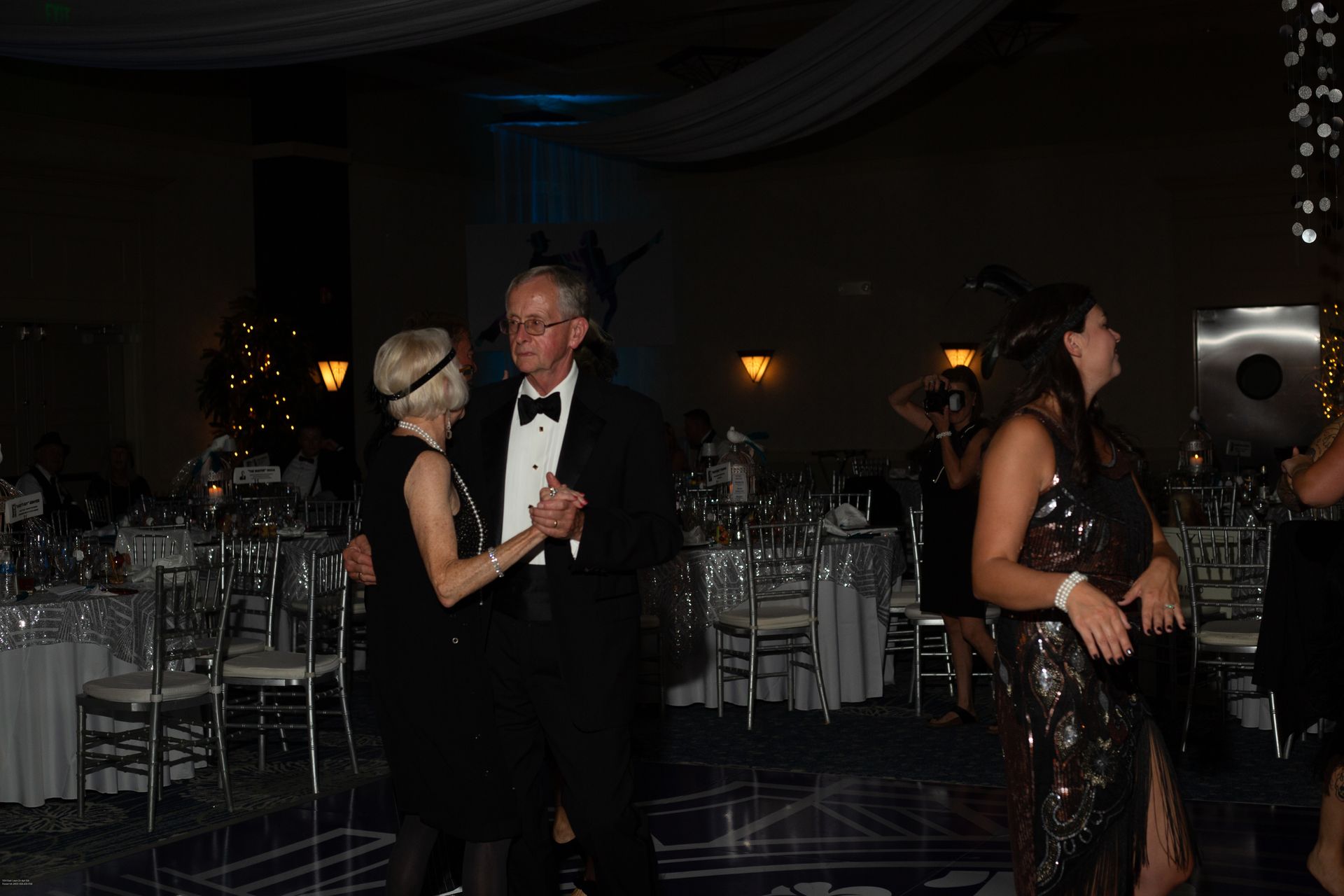 A man in a tuxedo is dancing with a woman in a black dress.