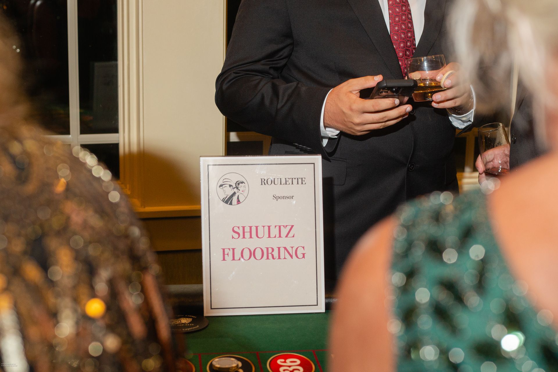 A man in a suit and tie is standing next to a sign that says shultz flooring.