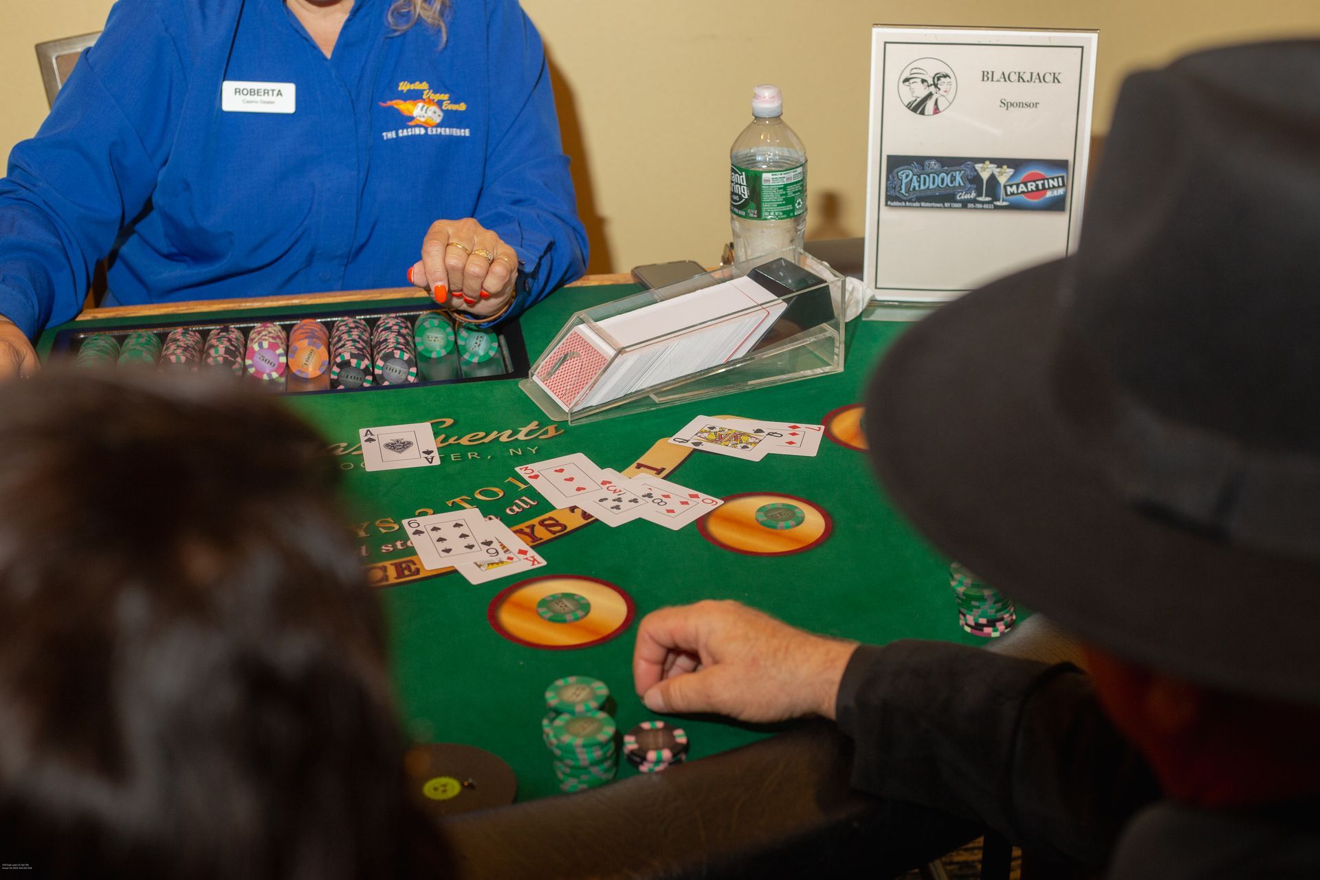 A woman in a blue shirt is sitting at a poker table