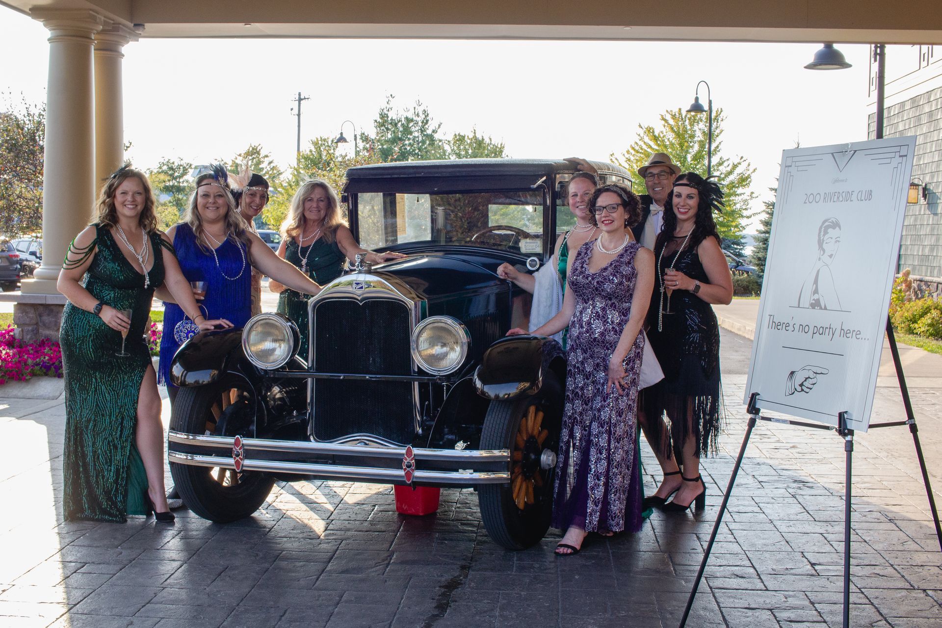 A group of people are posing for a picture in front of an old car.