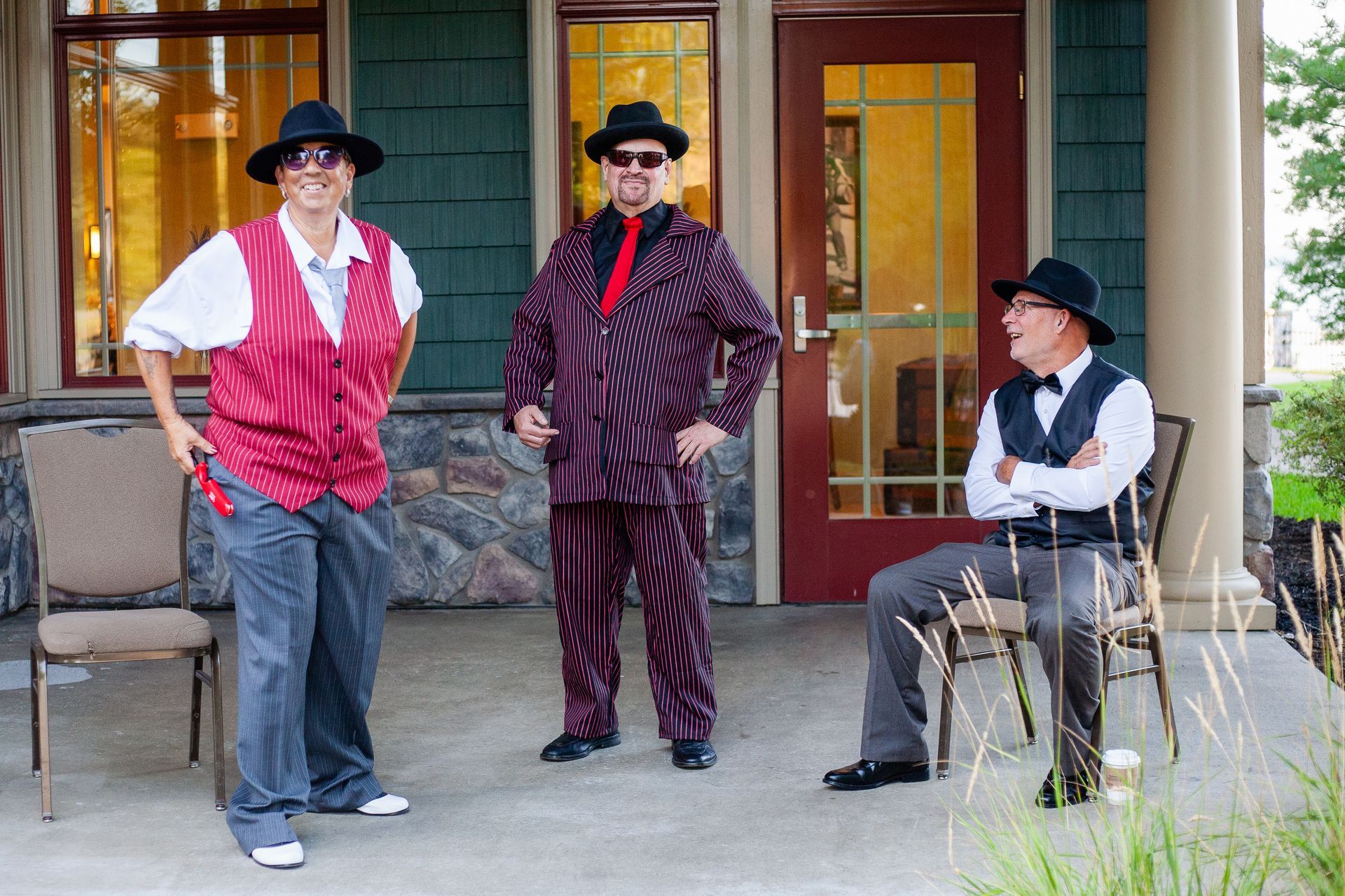 Three men in suits and hats are standing on a porch.