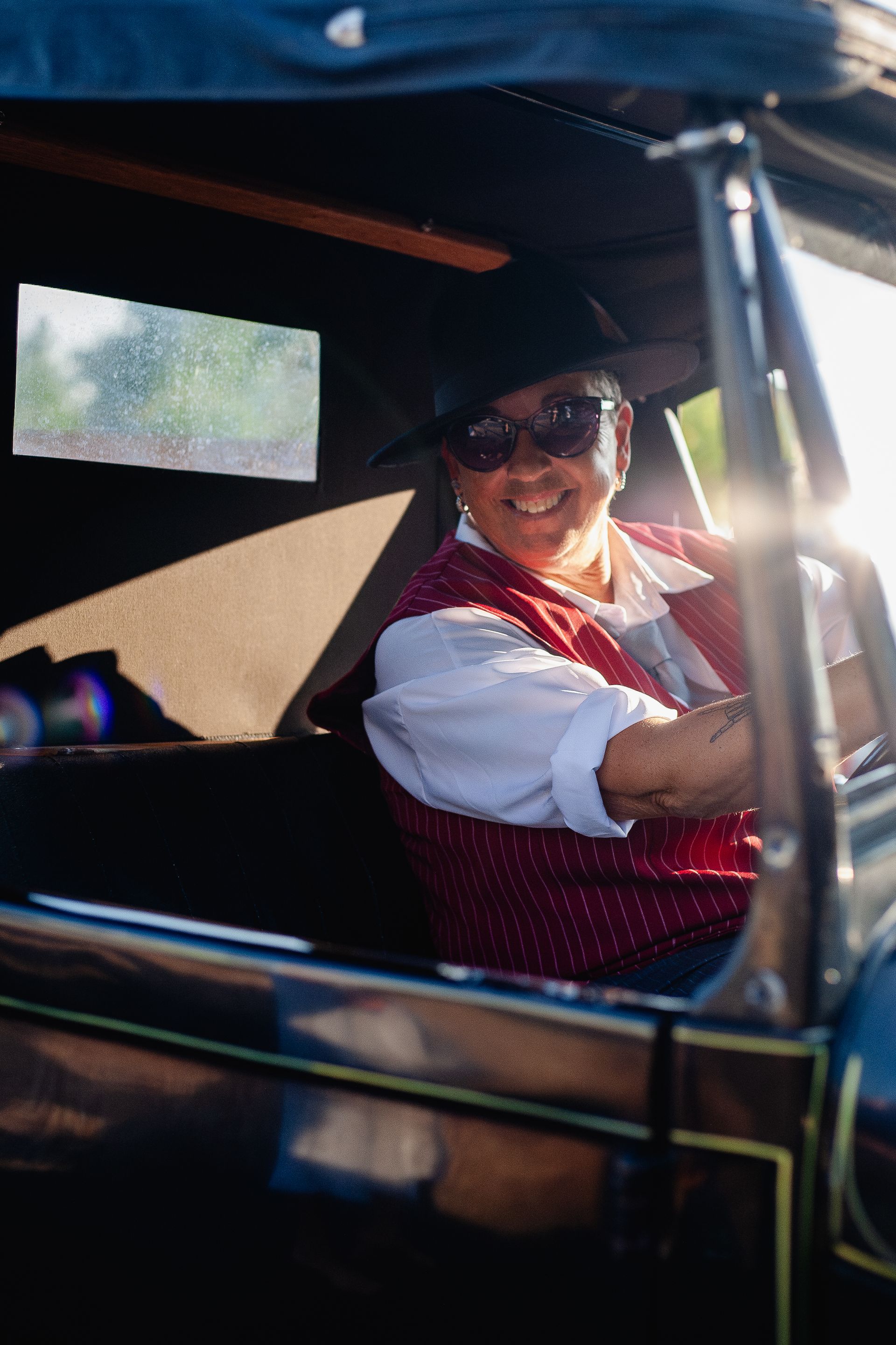 A woman is sitting in the driver 's seat of an old car.