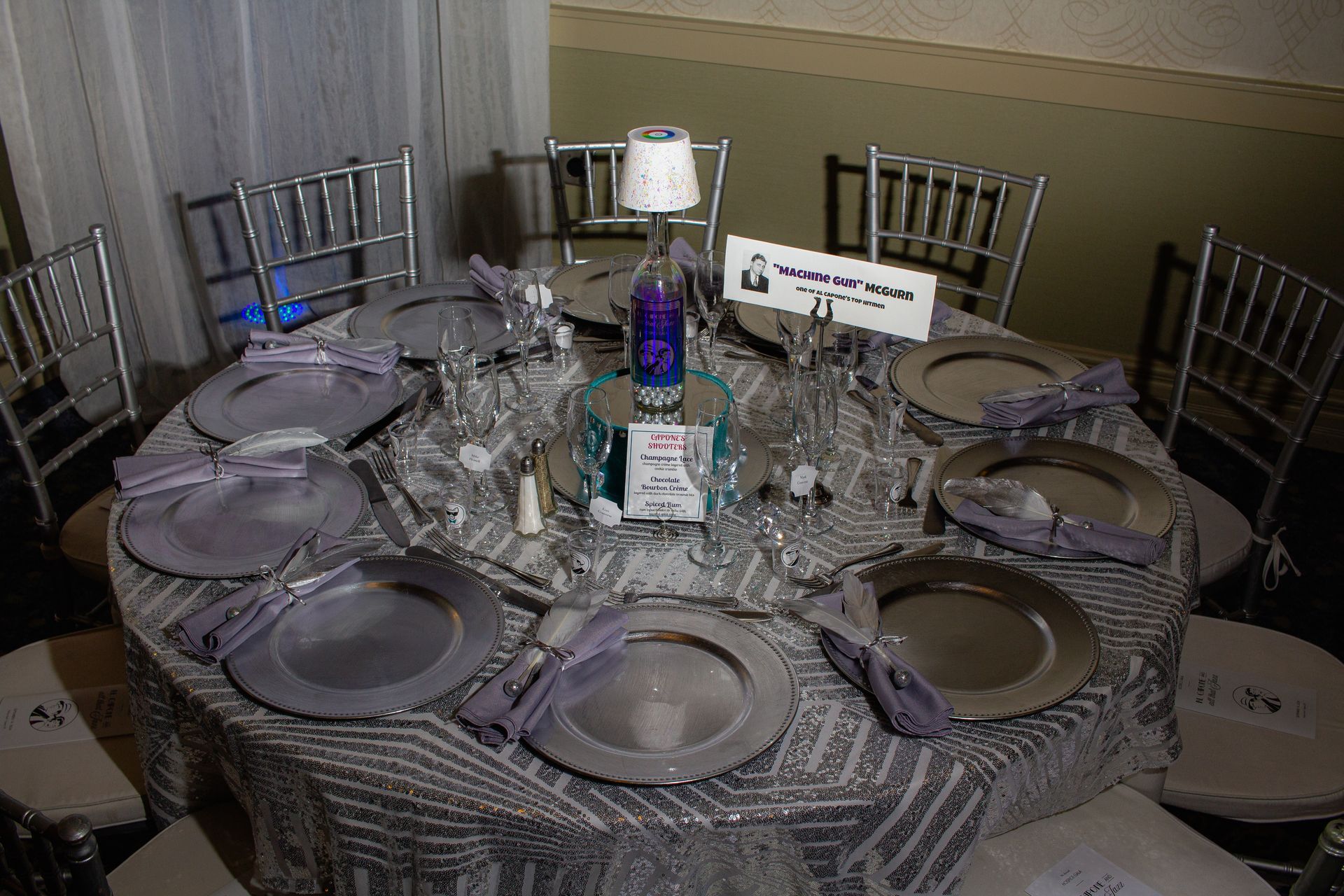 A table with plates , napkins , glasses and a lamp on it.