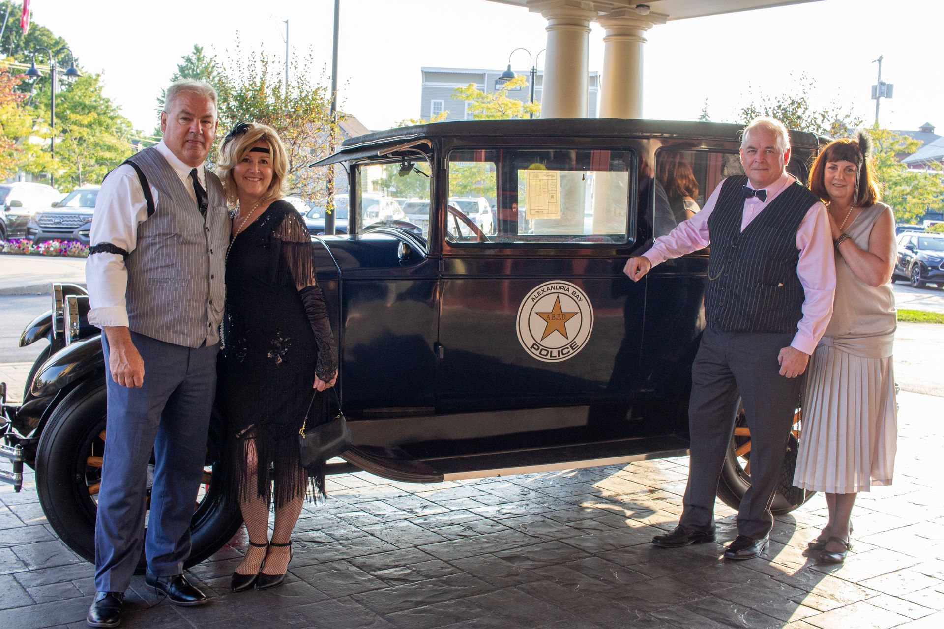 A group of people are standing in front of an old car.