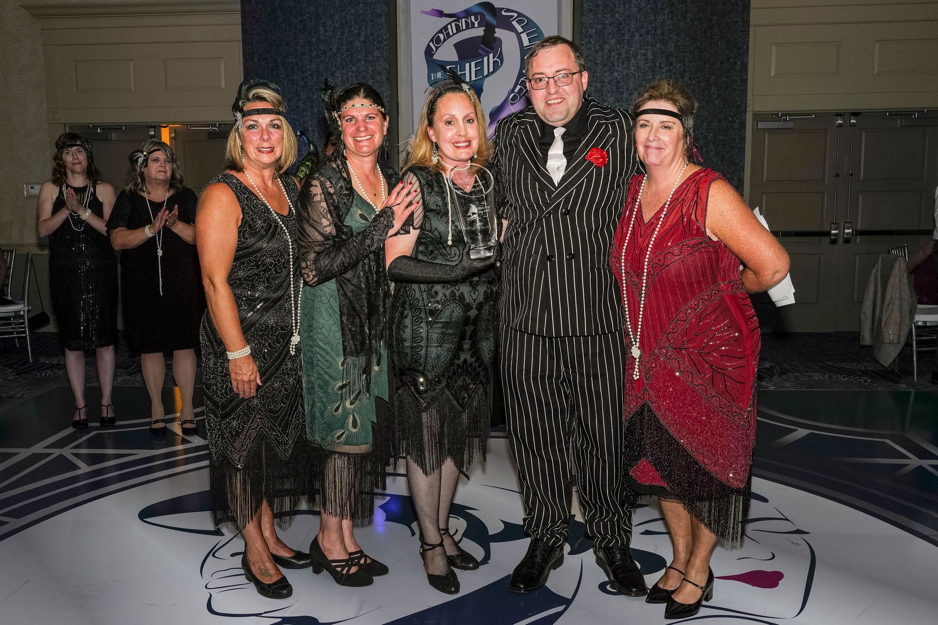 A group of people in flapper dresses are posing for a picture.
