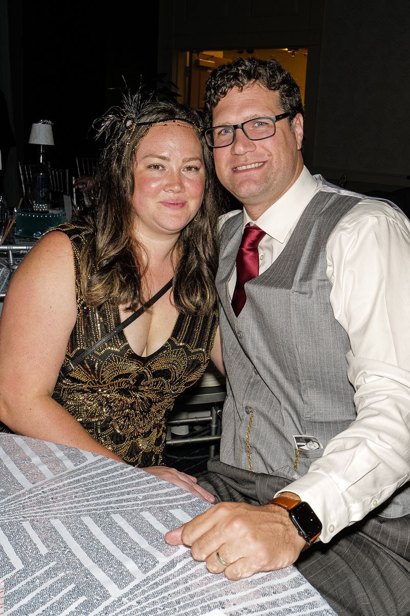A man and a woman are posing for a picture while sitting at a table.