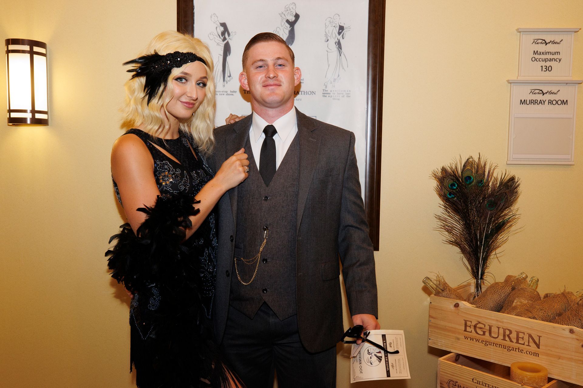 A man in a suit and tie is standing next to a woman in a flapper dress.