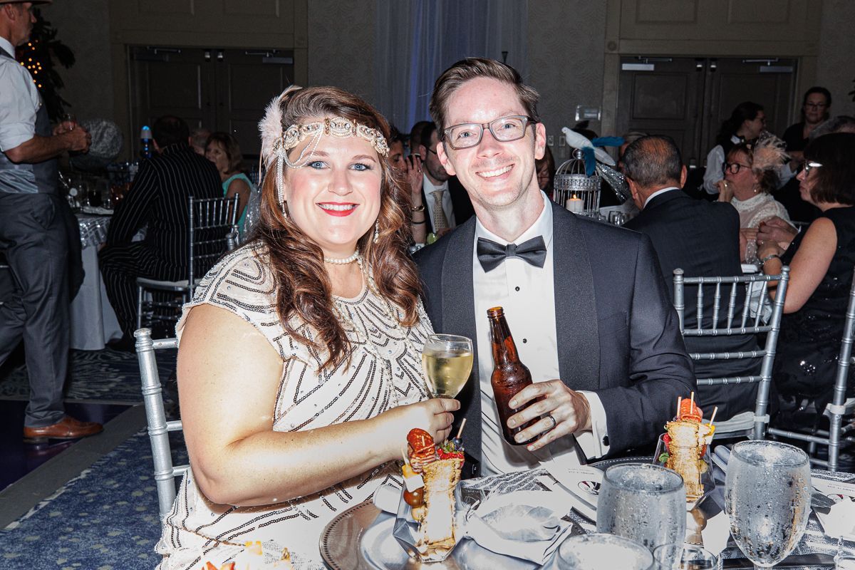 A man and a woman are sitting at a table with a bottle of beer.