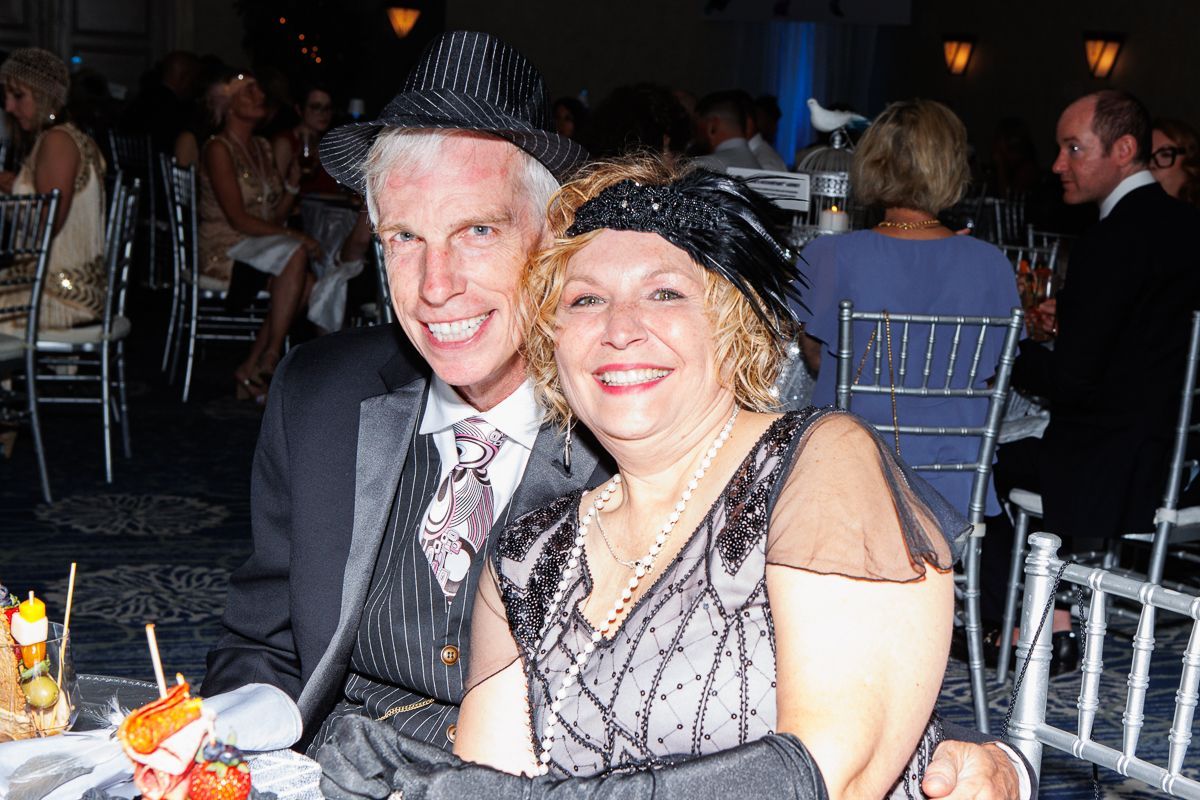 A man and a woman are posing for a picture while sitting at a table.