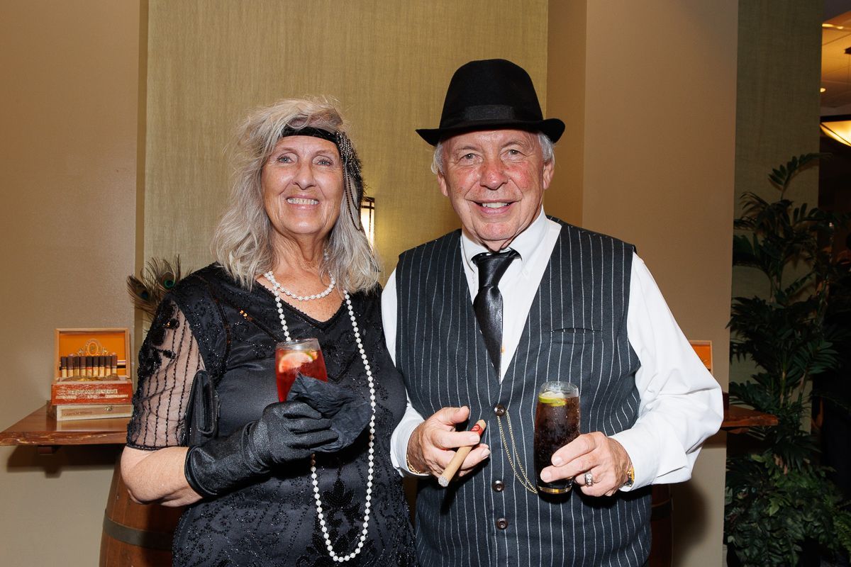 A man and a woman are standing next to each other holding drinks.