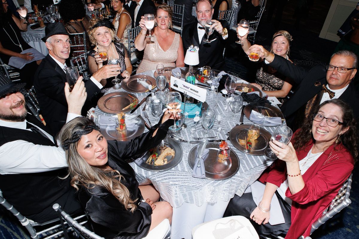 A group of people are sitting at a table toasting with wine glasses.