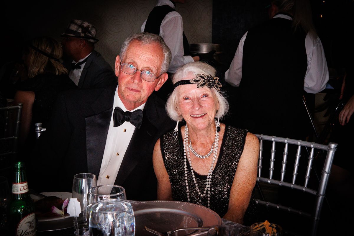 A man and a woman are sitting at a table at a party.